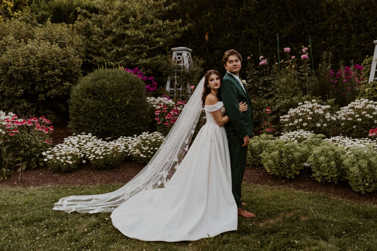 Garden wedding portrait with flowering bushes and natural landscape.