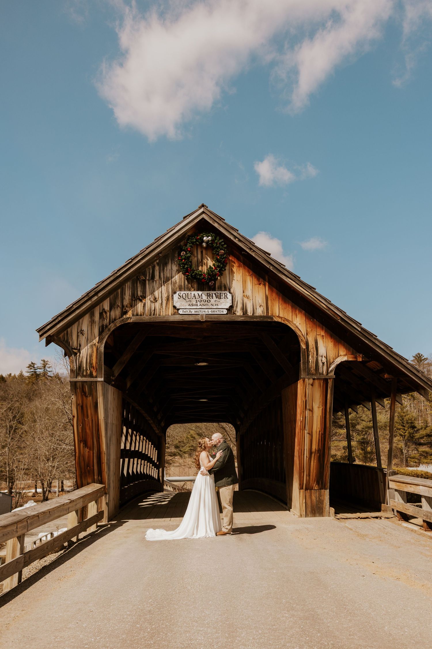 A rustic wooden covered bridge photographed from multiple angles on a sunny day with blue skies.