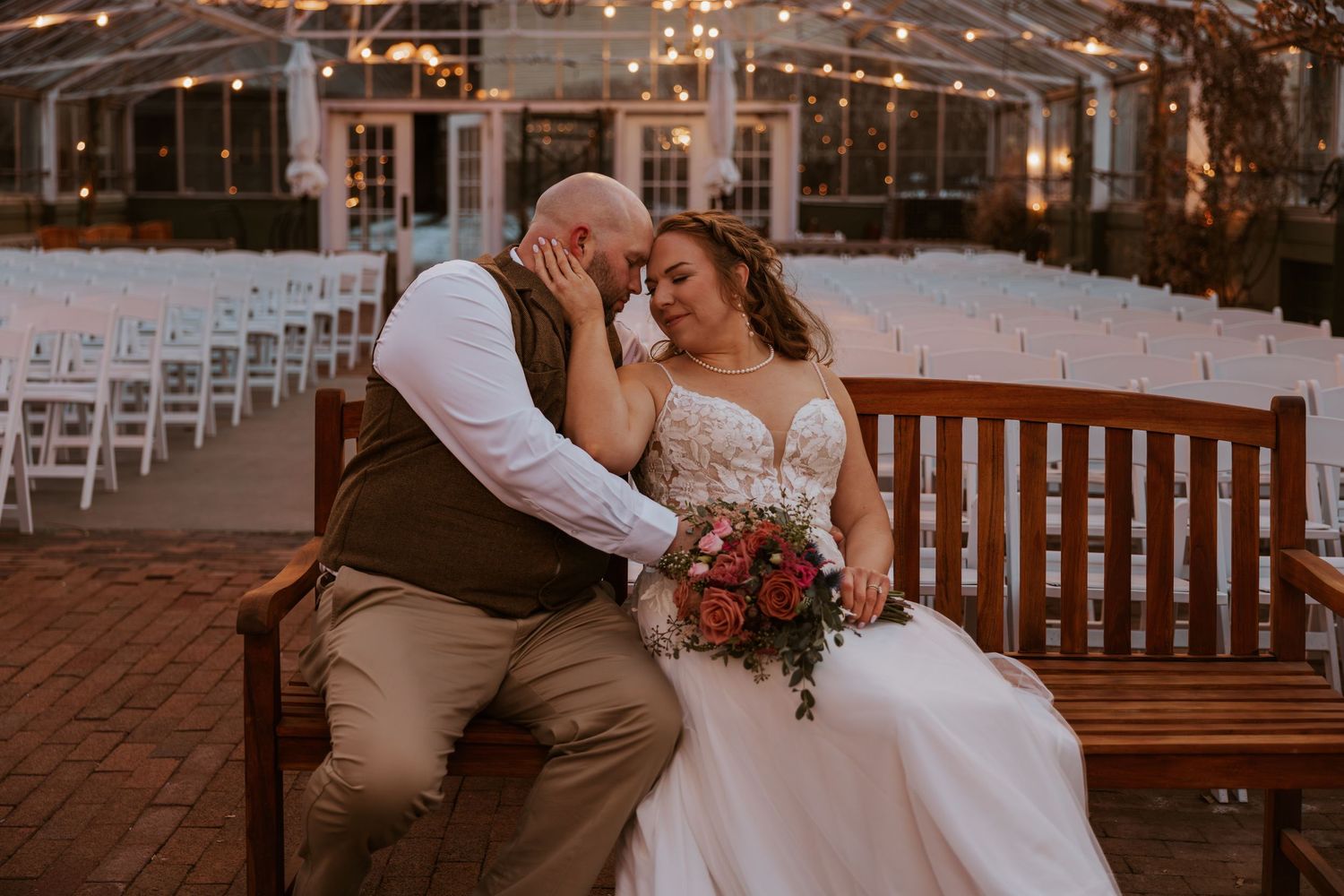 Romantic outdoor wedding ceremony at sunset with string lights and garden setting.