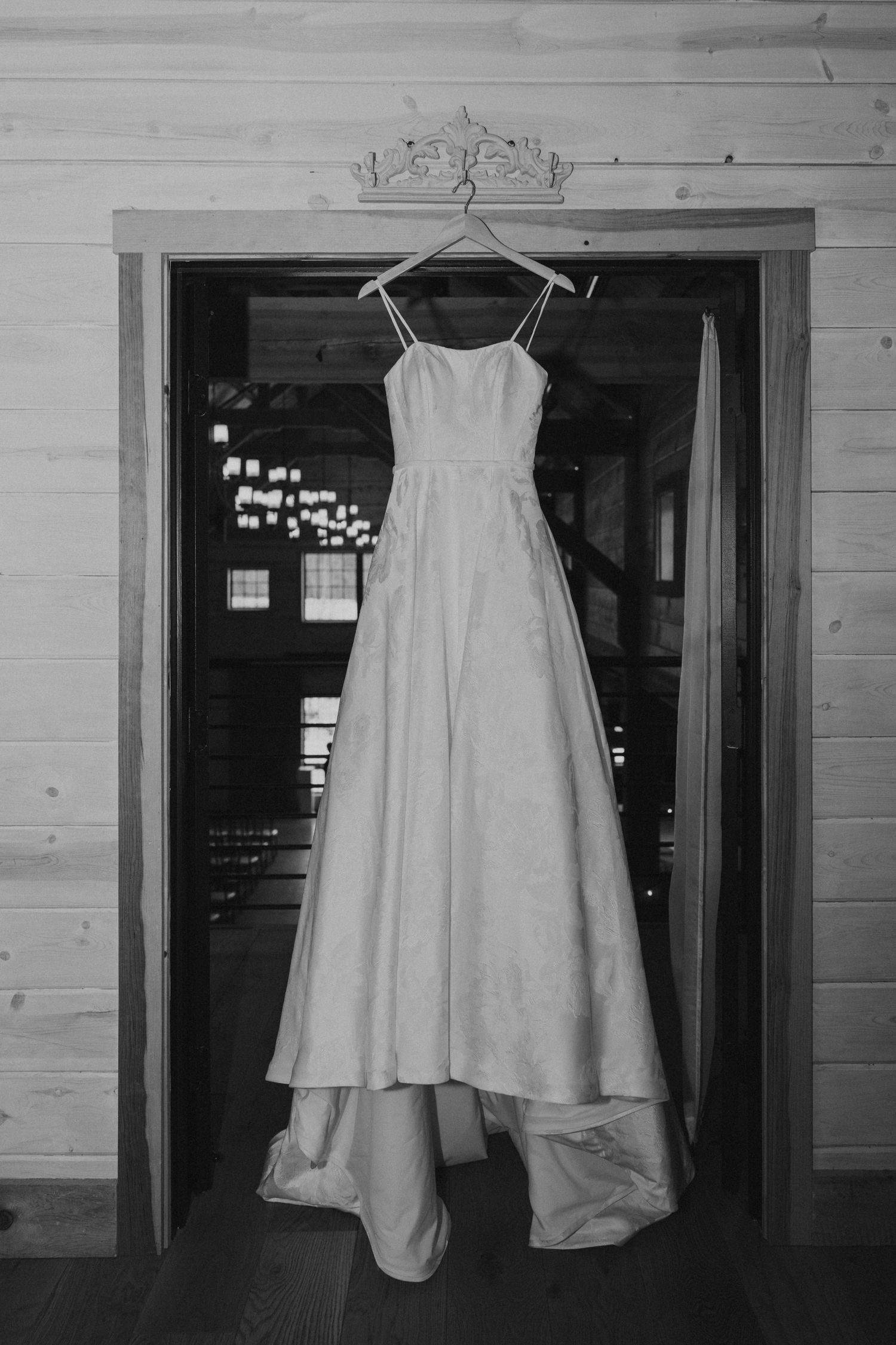 A wedding dress hanging in the doorway in black and white.