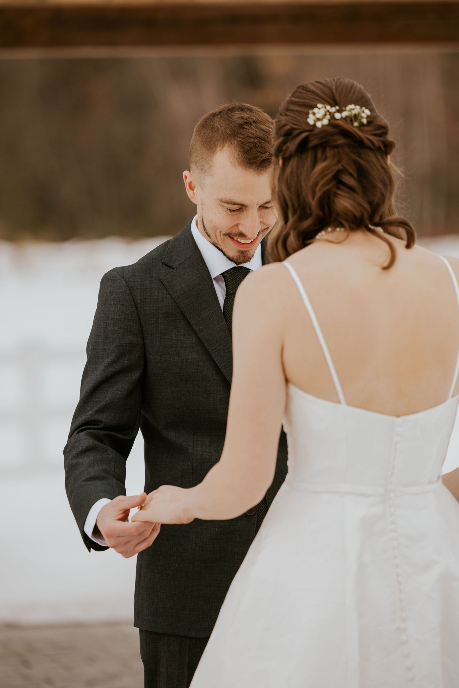 A romantic winter wedding first look moment captured in a series of intimate photos against a snowy backdrop.