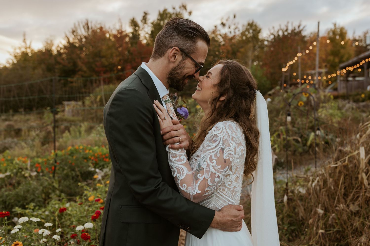 Bride and groom sharing a romantic kiss in a colorful autumn garden at sunset.
