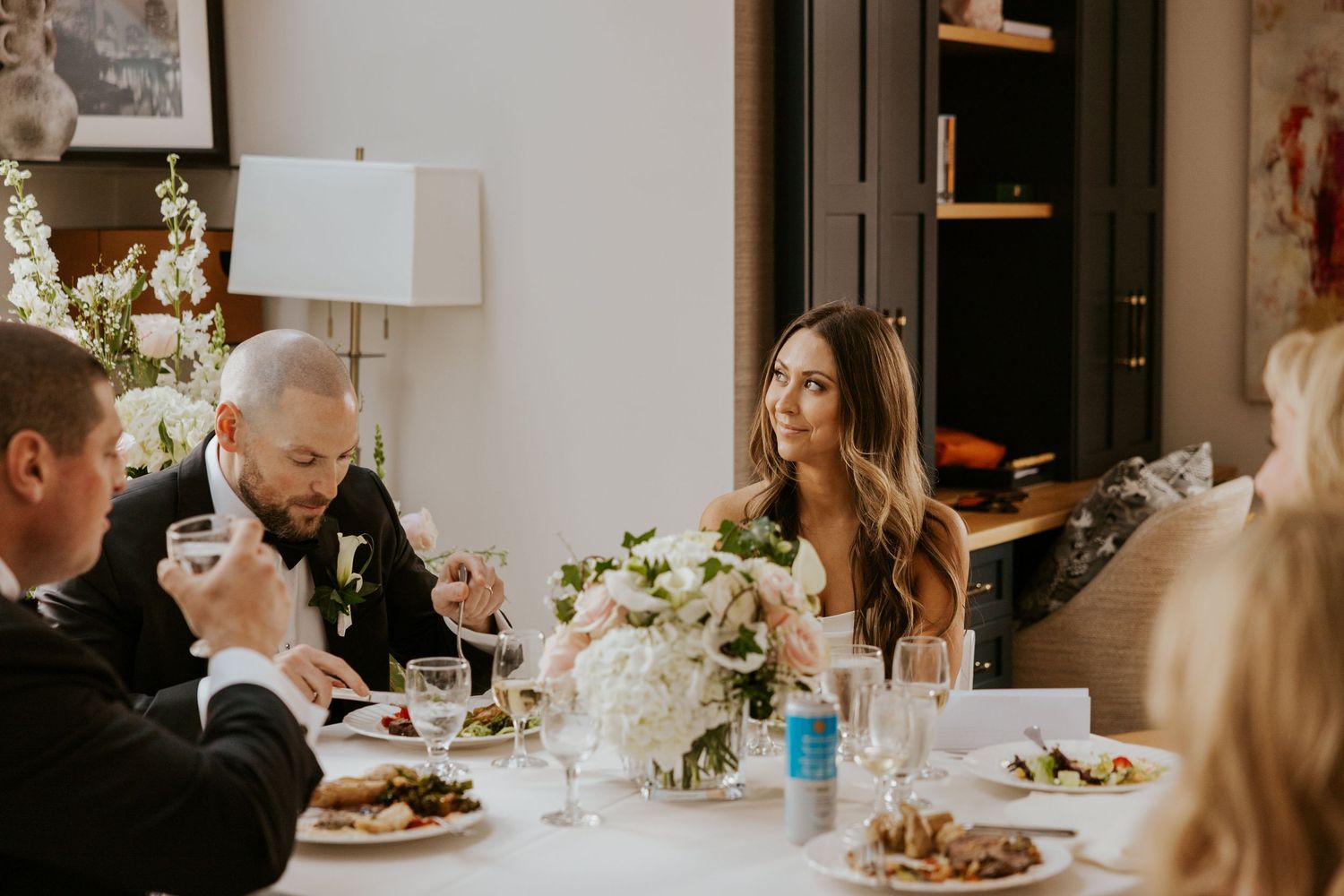 Wedding reception dinner scene with guests seated at tables in an elegant indoor venue.