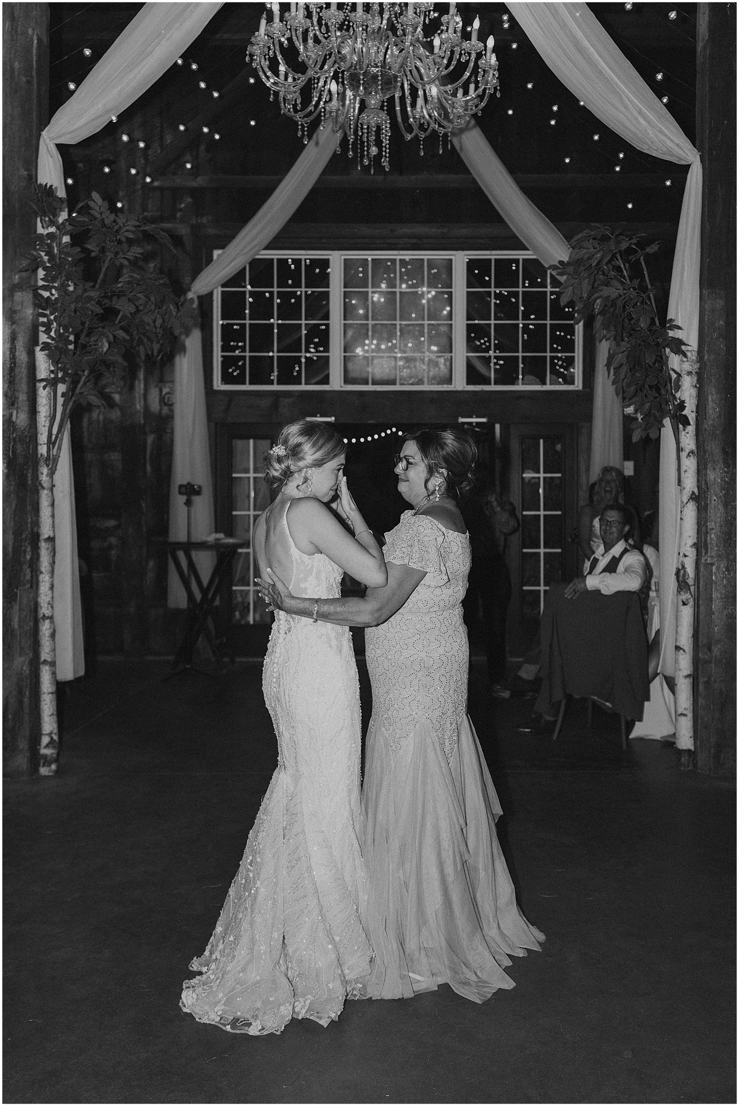 Black and white photo of couples dancing in a rustic barn reception venue.