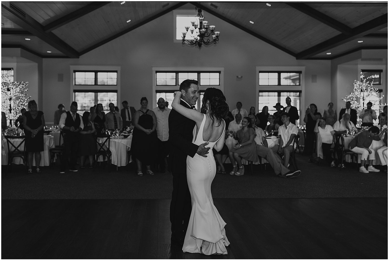 Wedding reception venue with exposed wooden beams and elegant lighting setup.