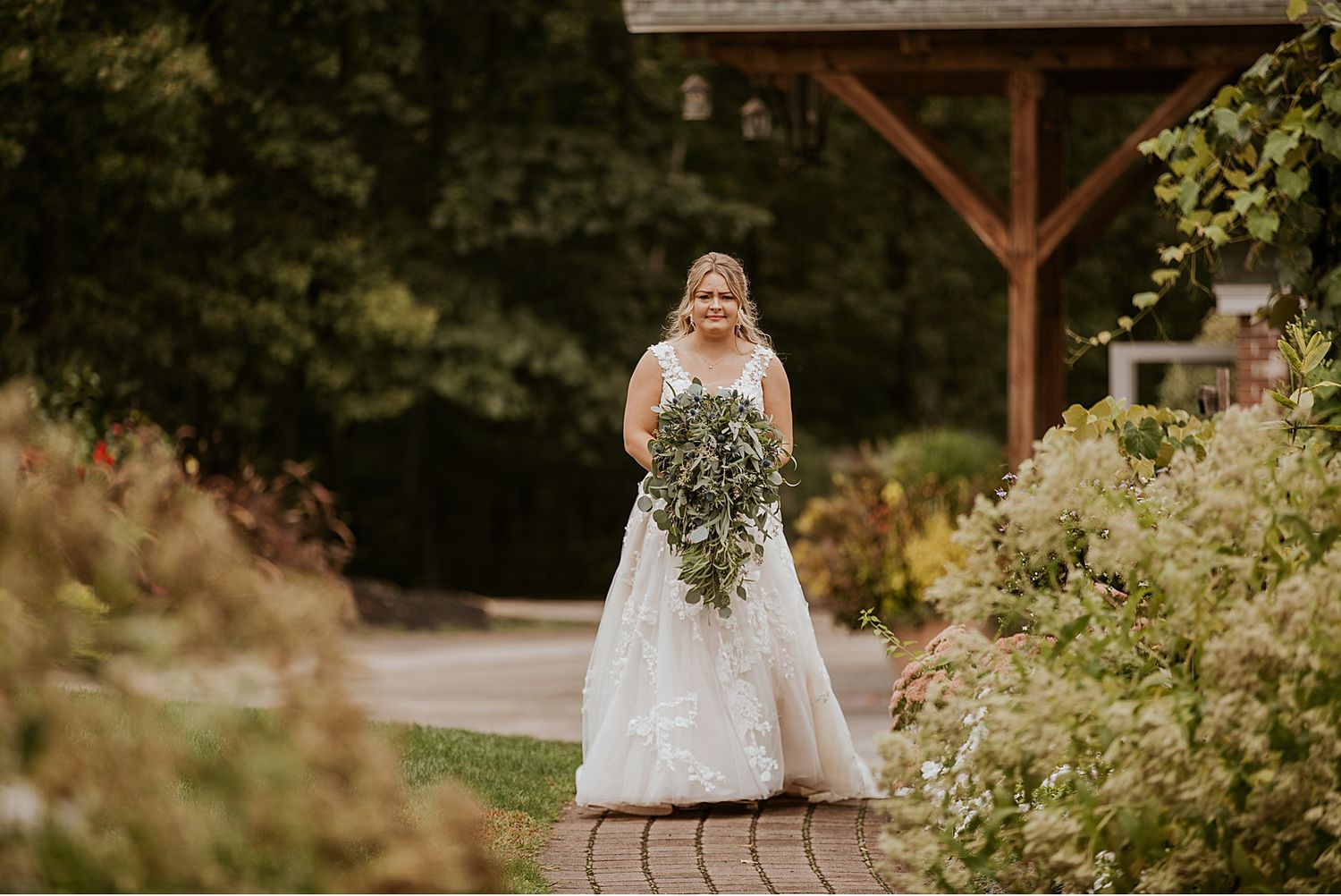 Rustic outdoor wedding venue with wooden beams and natural landscaping.