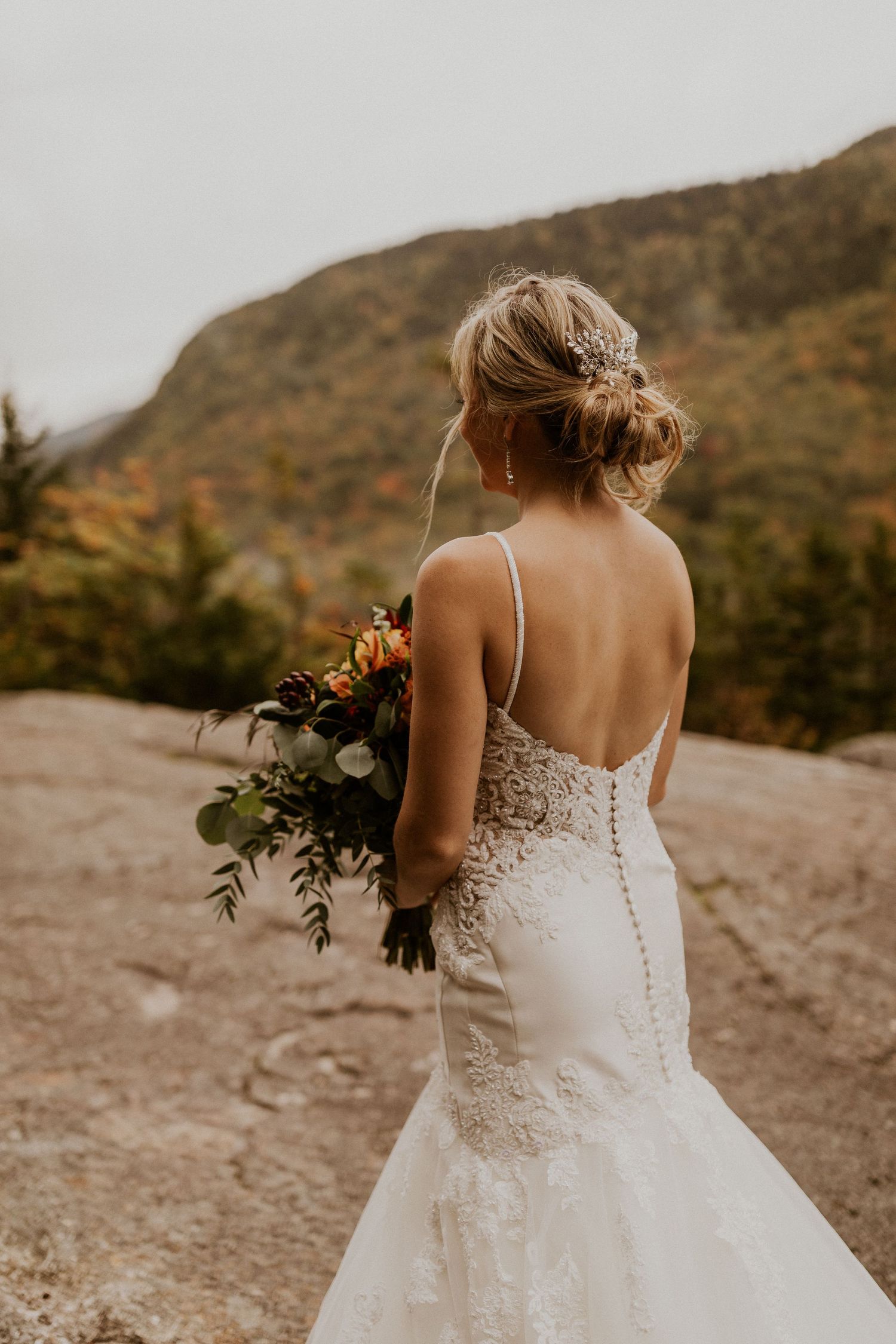 The bride waiting for her groom to come around the corner and see her for the very first time on top of the mountain.