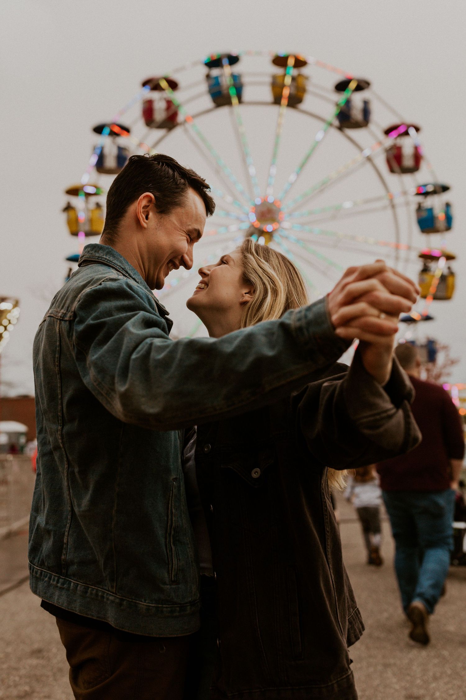 Dancing couple silhouetted against a ferris wheel at dusk.