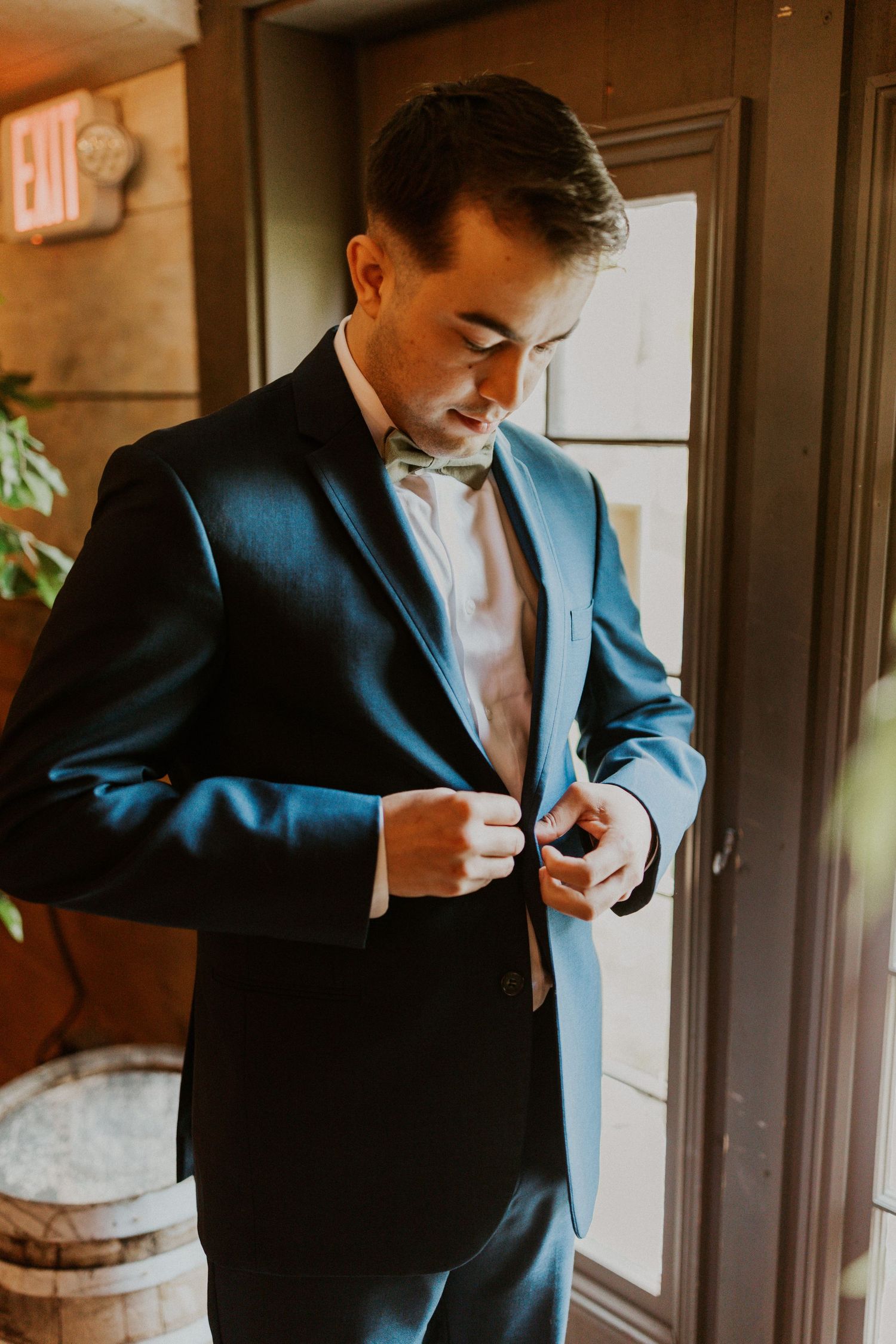 Mike buttoning his suit jacket as he gets ready for the wedding ceremony.