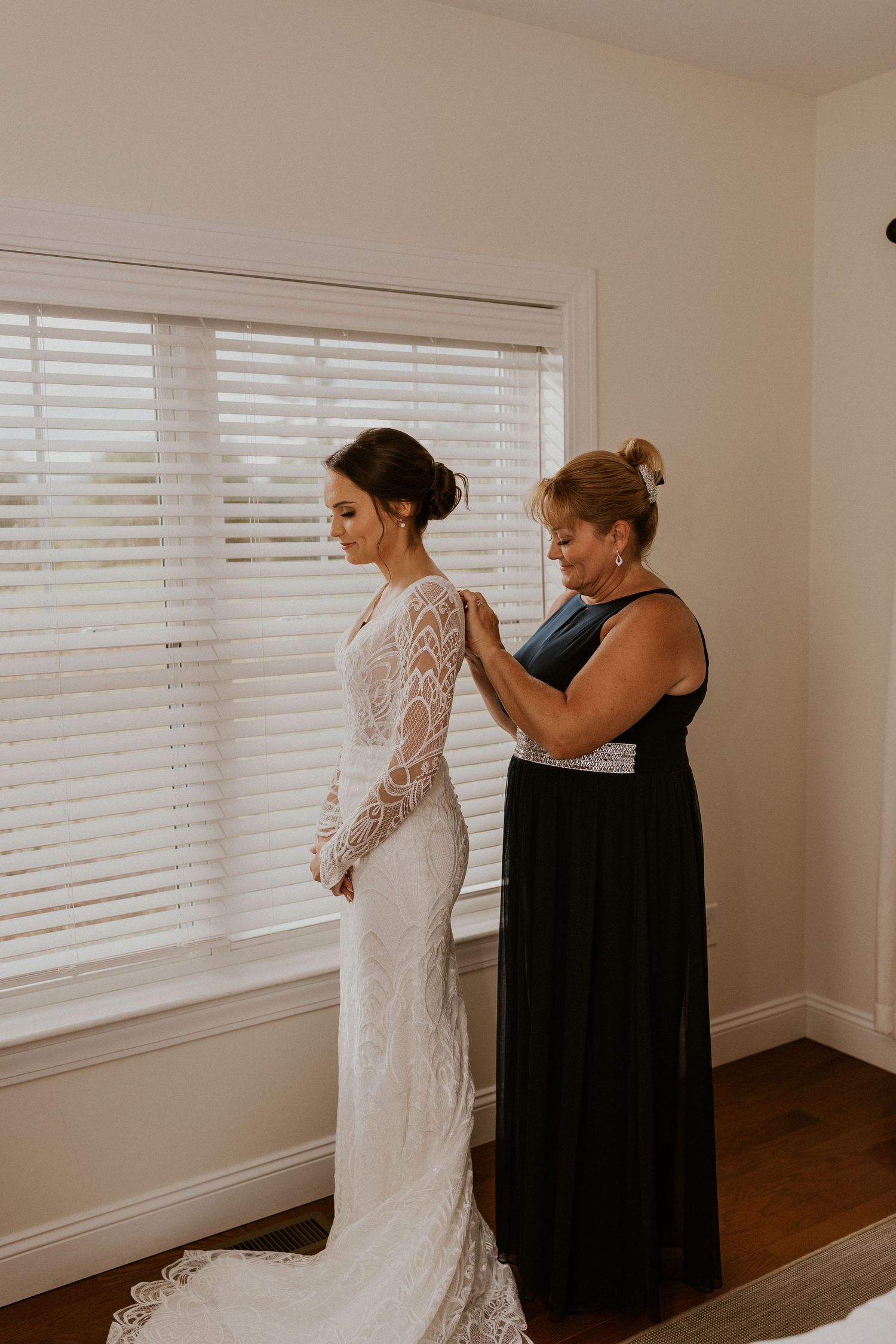The bride's mother helping button her wedding gown.