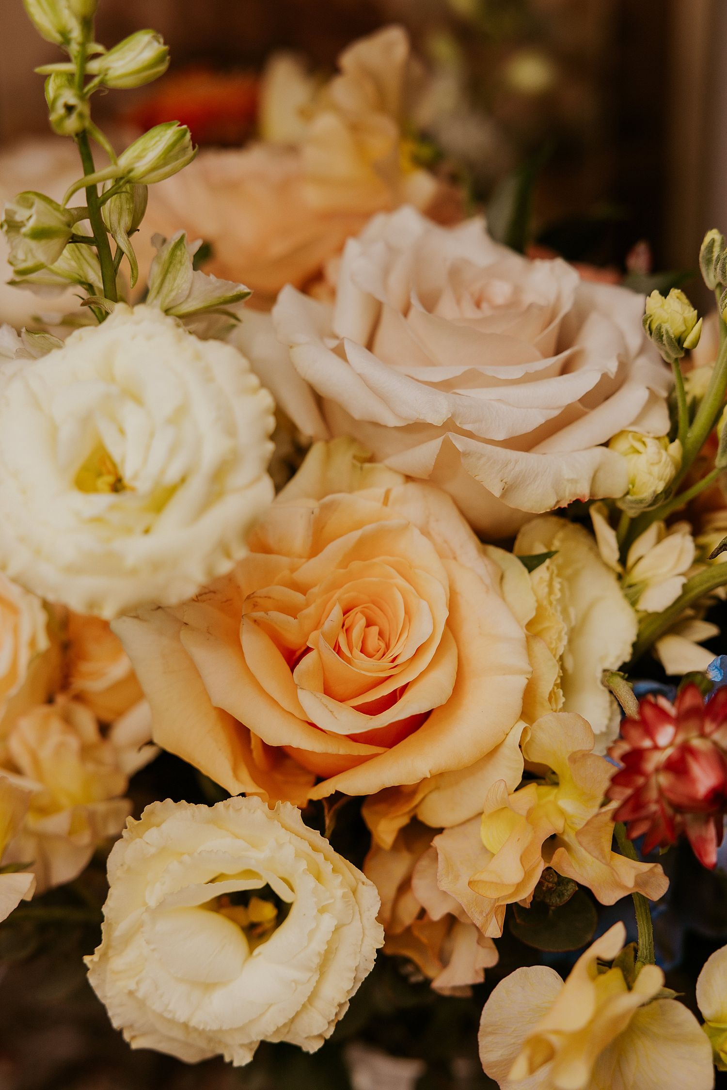 Close up of bridal bouquet made up of orange, peach, cream and blush pink flowers for a NH wedding