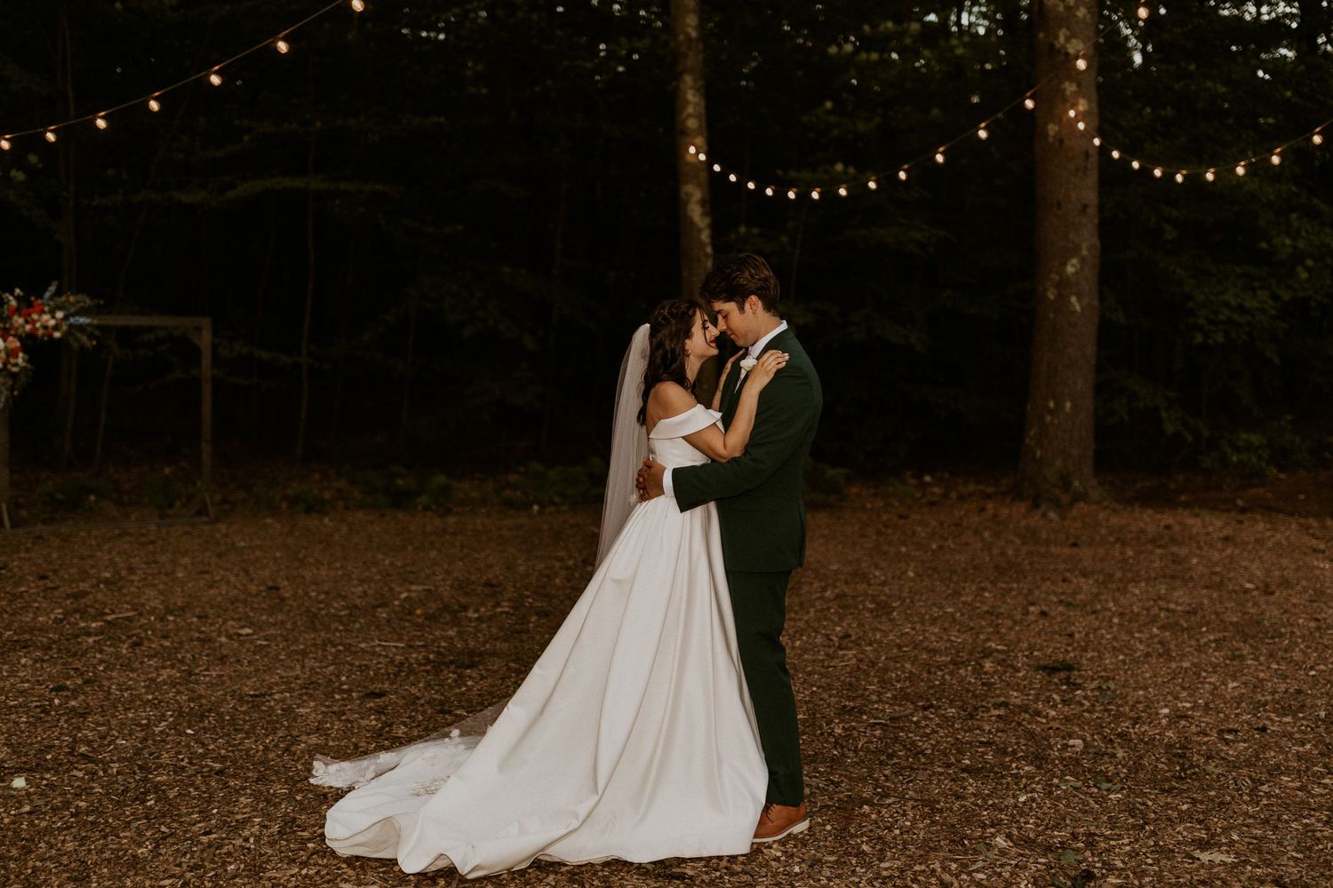 Twinkling string lights create magical ambiance in wooded wedding setting.