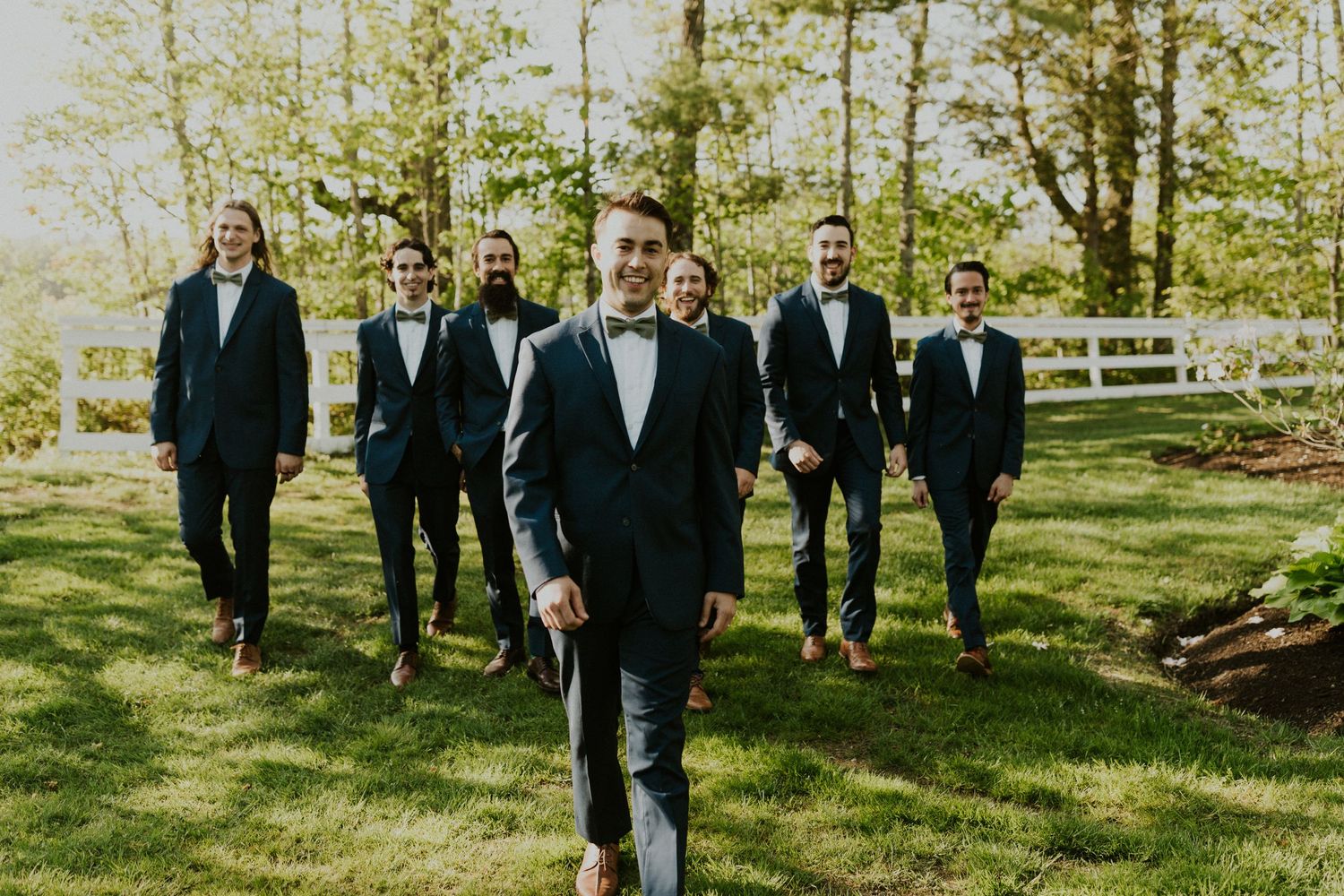 Groomsmen group photos. Mike is walking in front of the group, smiling at the camera.