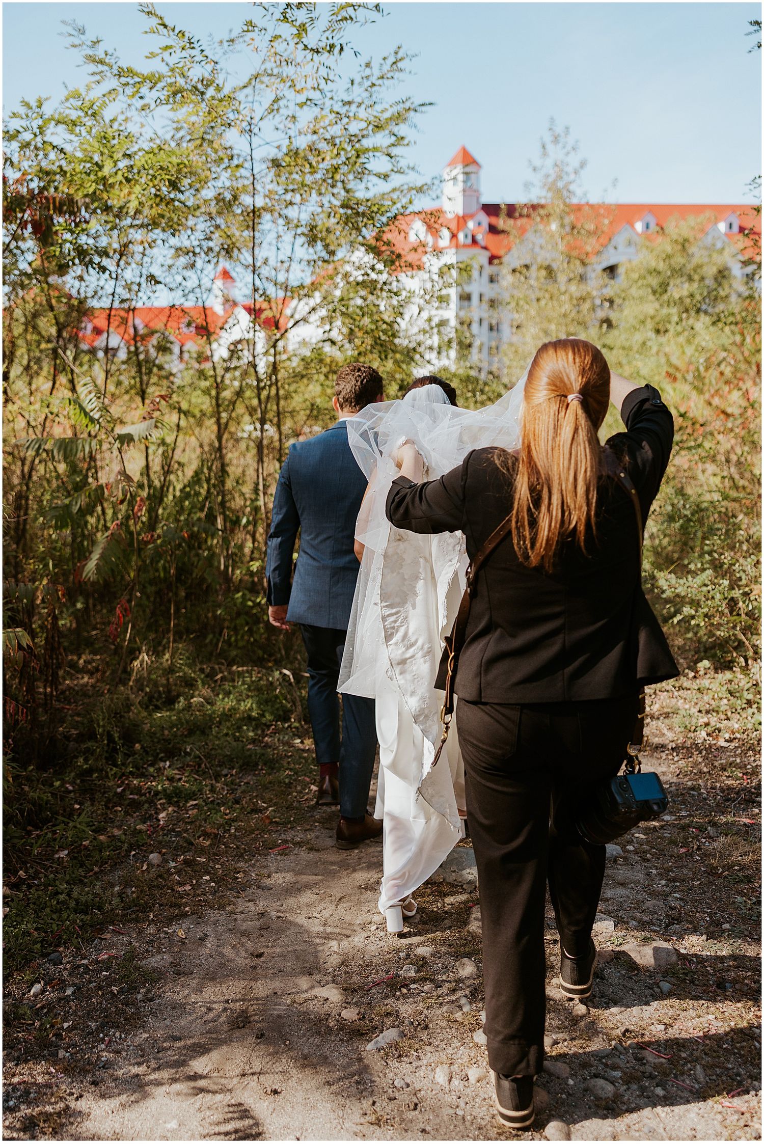 New Hampshire wedding photographer helping a bride with her train