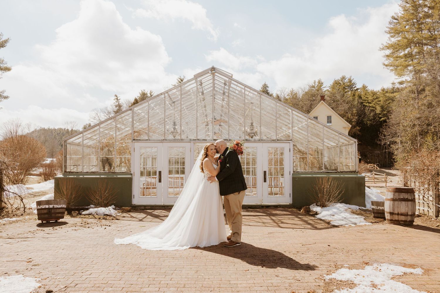 Rustic greenhouse wedding venue exterior with string lights and mountain backdrop.
