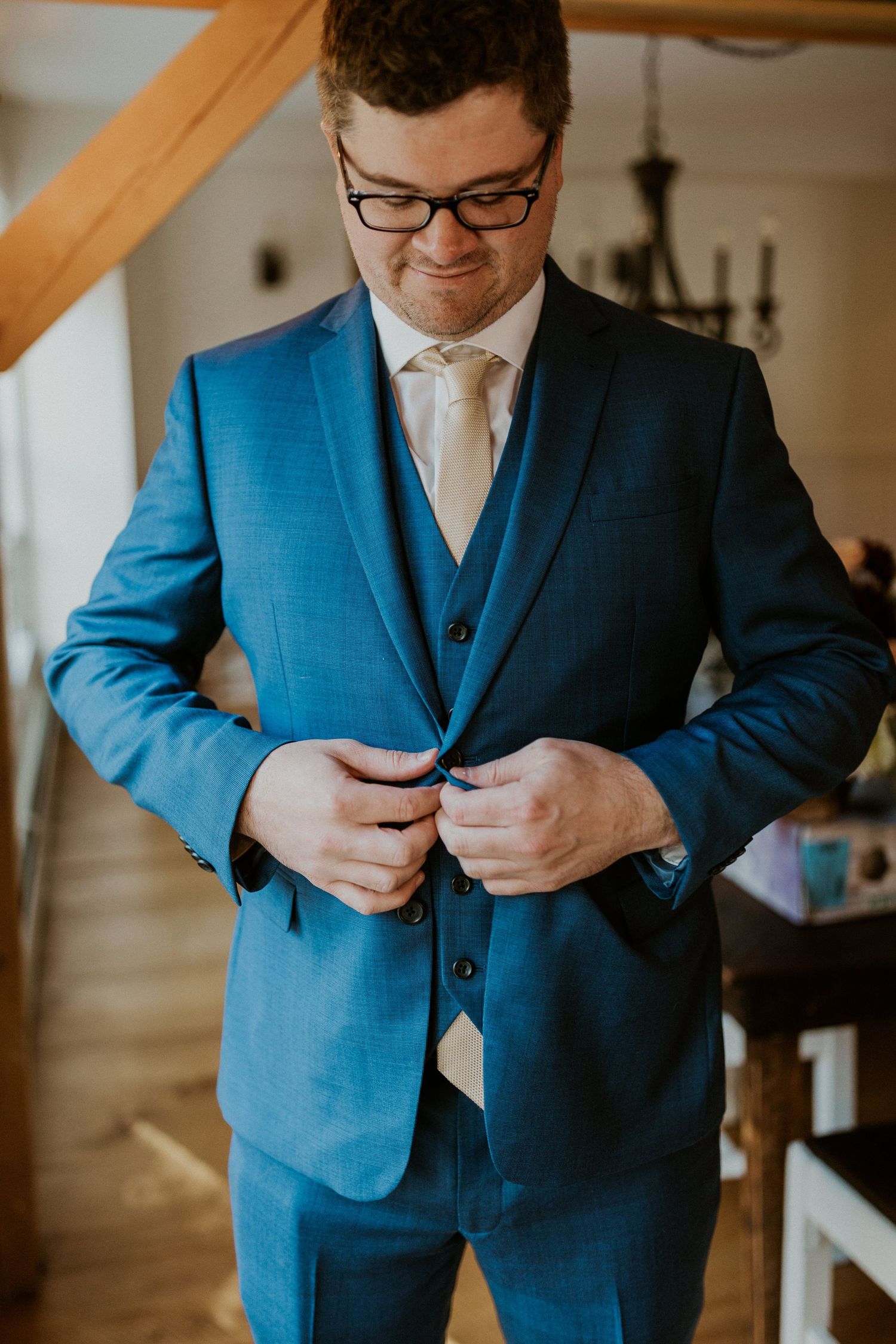 Daniel buttoning his suit as he prepares for the wedding.