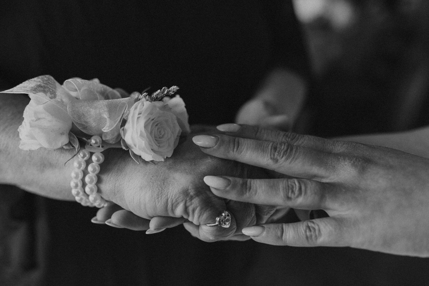 A black and white detail photo of Kendra and her mother holding hands while getting ready for the wedding.