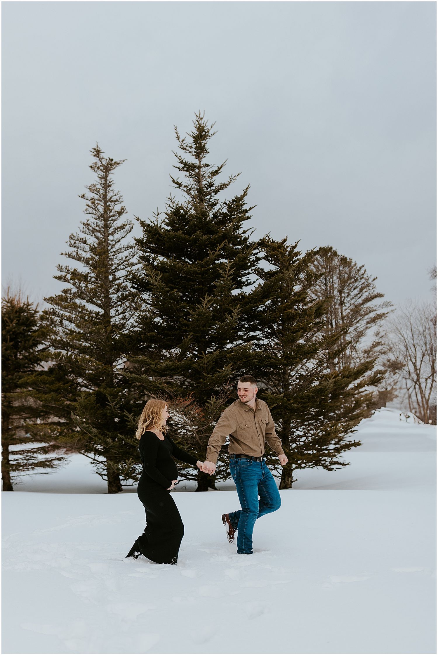 Couple taking maternity photos in the snow in NH