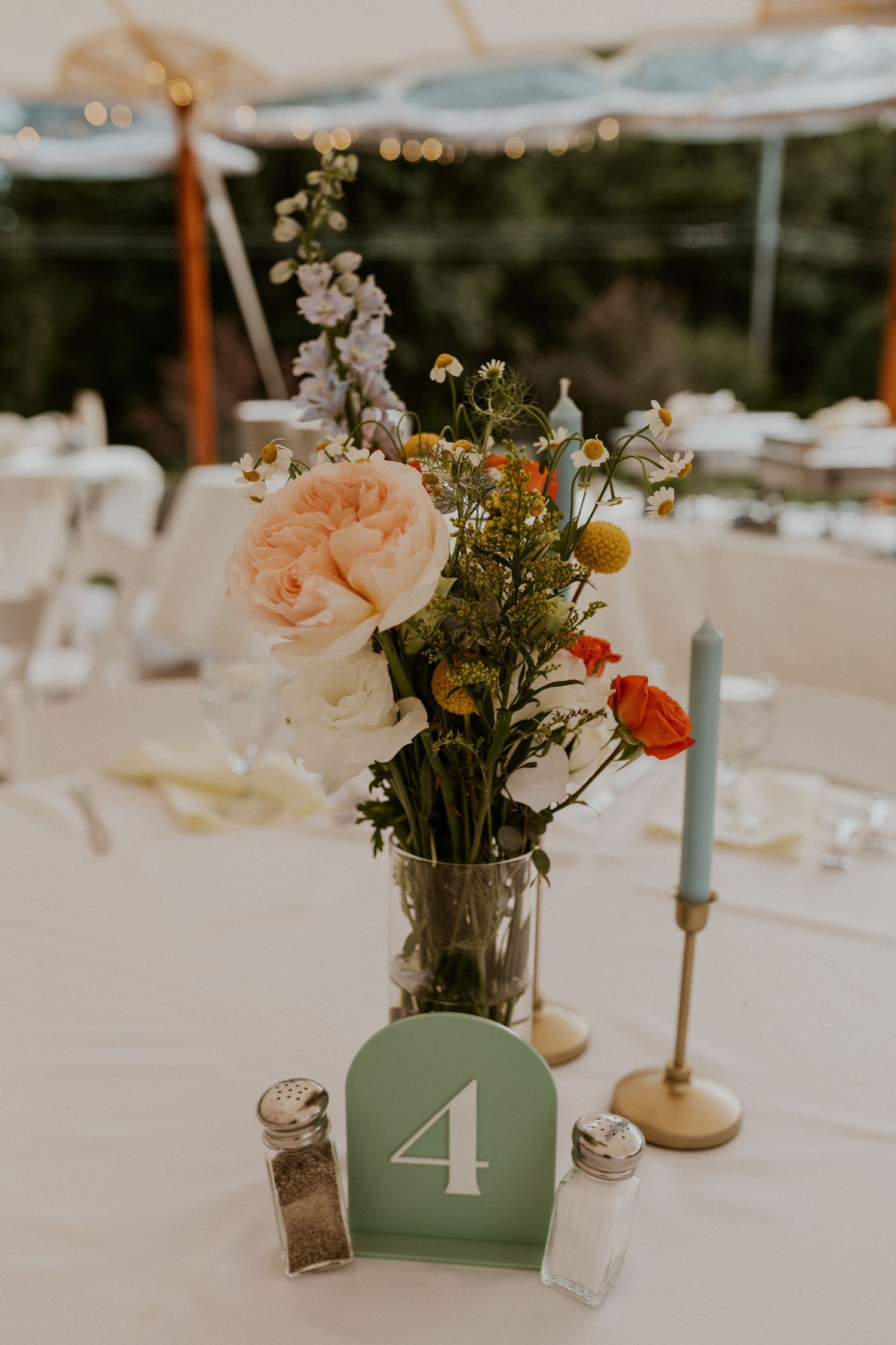 Wedding table centerpiece with peach roses and table number in sage green.