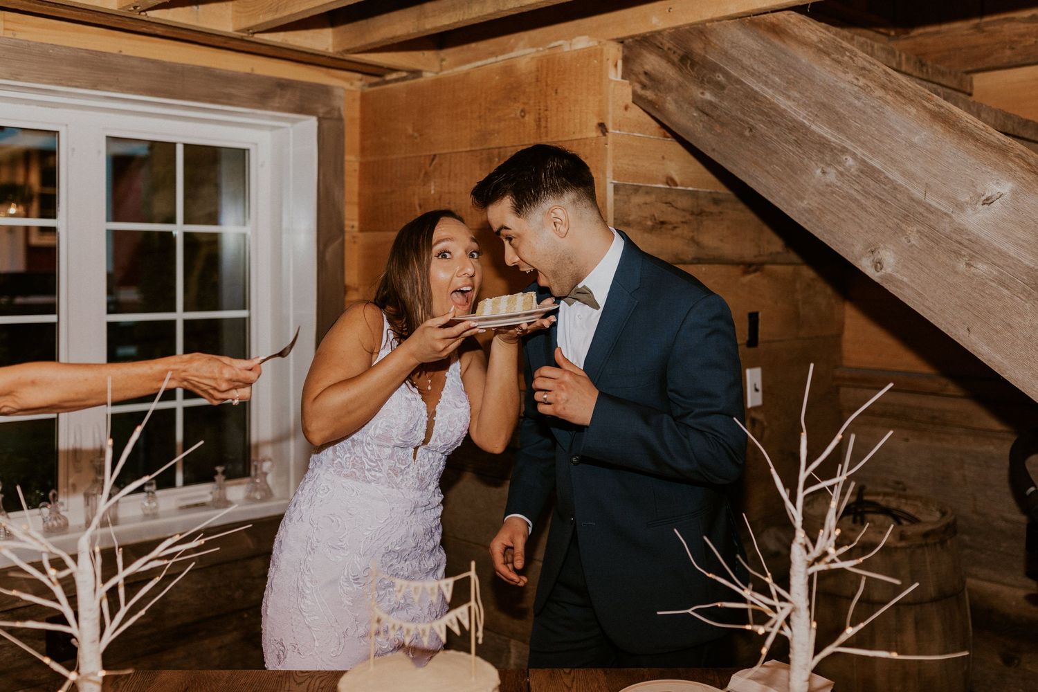 Romantic barn wedding reception with couples sharing intimate moments at decorated dining tables.