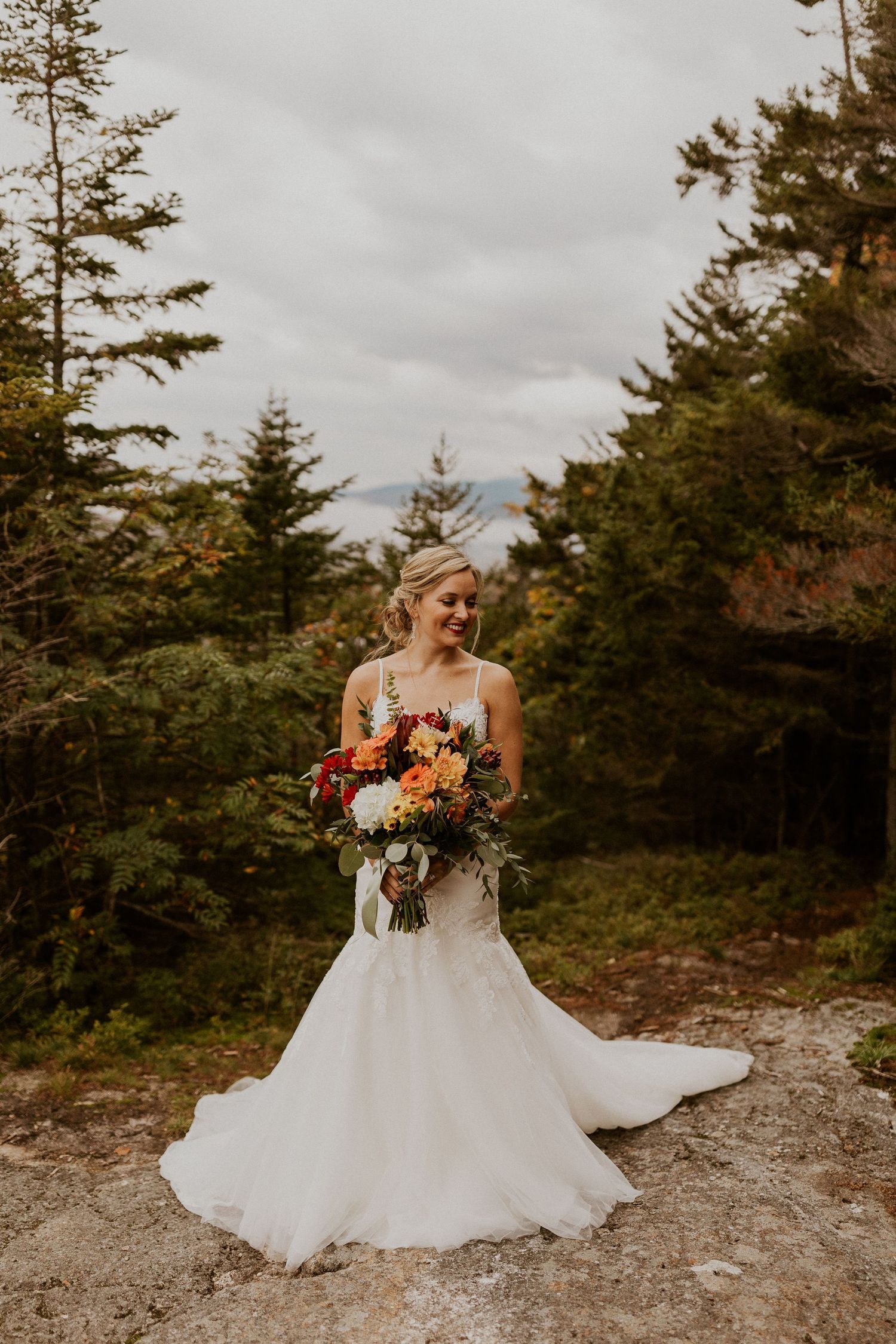 The bride waiting for her groom to come around the corner and see her for the very first time on top of the mountain.