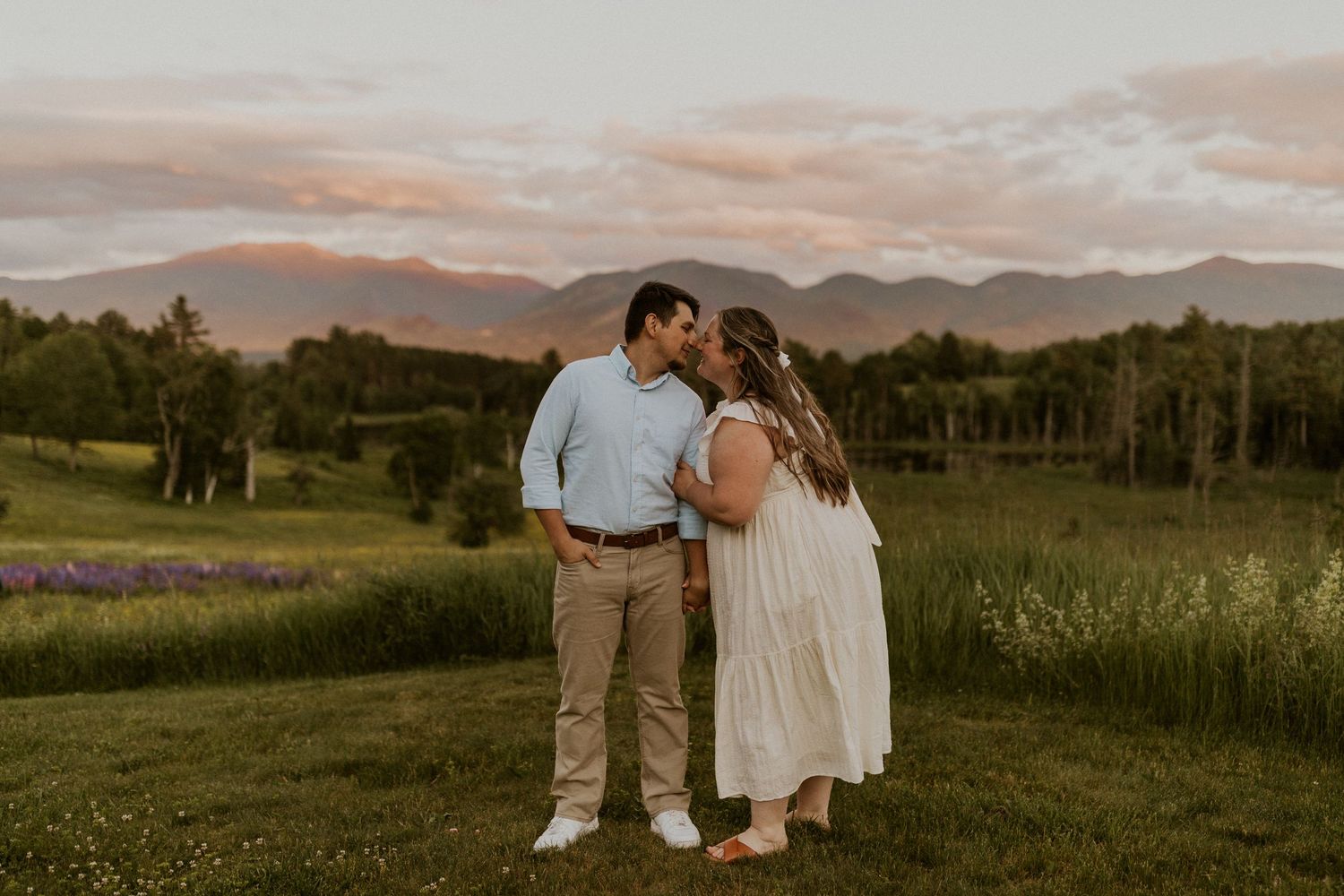 Terise hugging onto Jose's arm and smiling during an engagement photoshoot in the lupine fields of Sugar Hill NH.