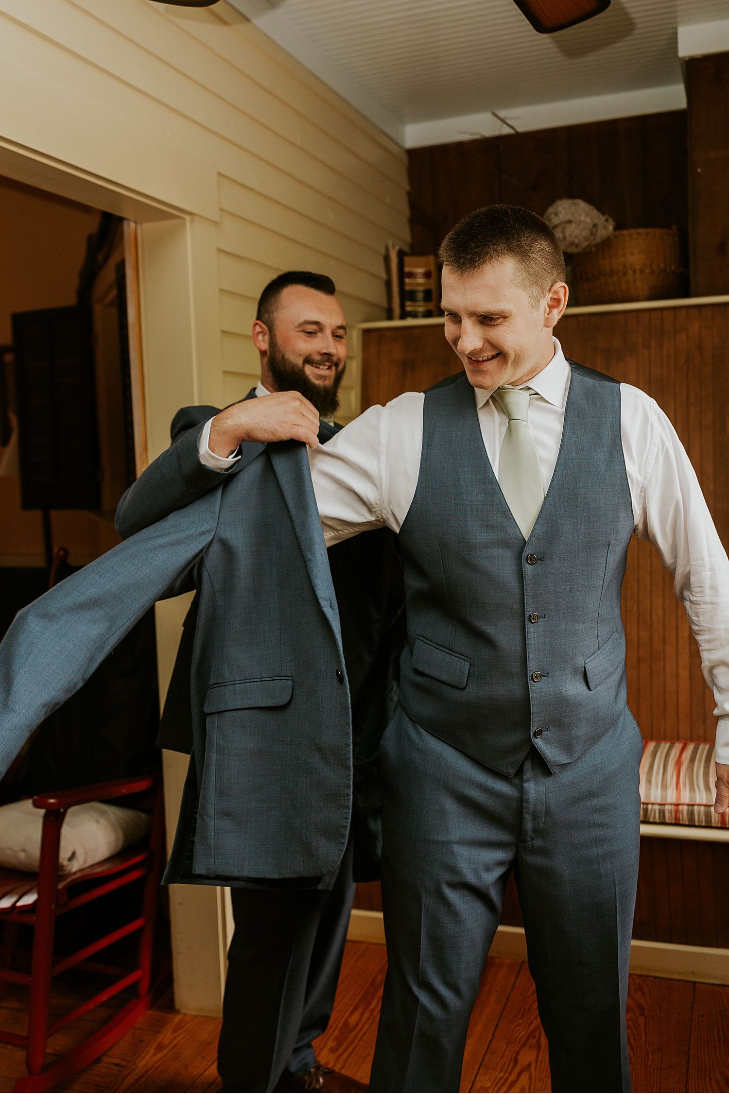 Groomsmen in grey vests sharing laughs while getting ready for the wedding.