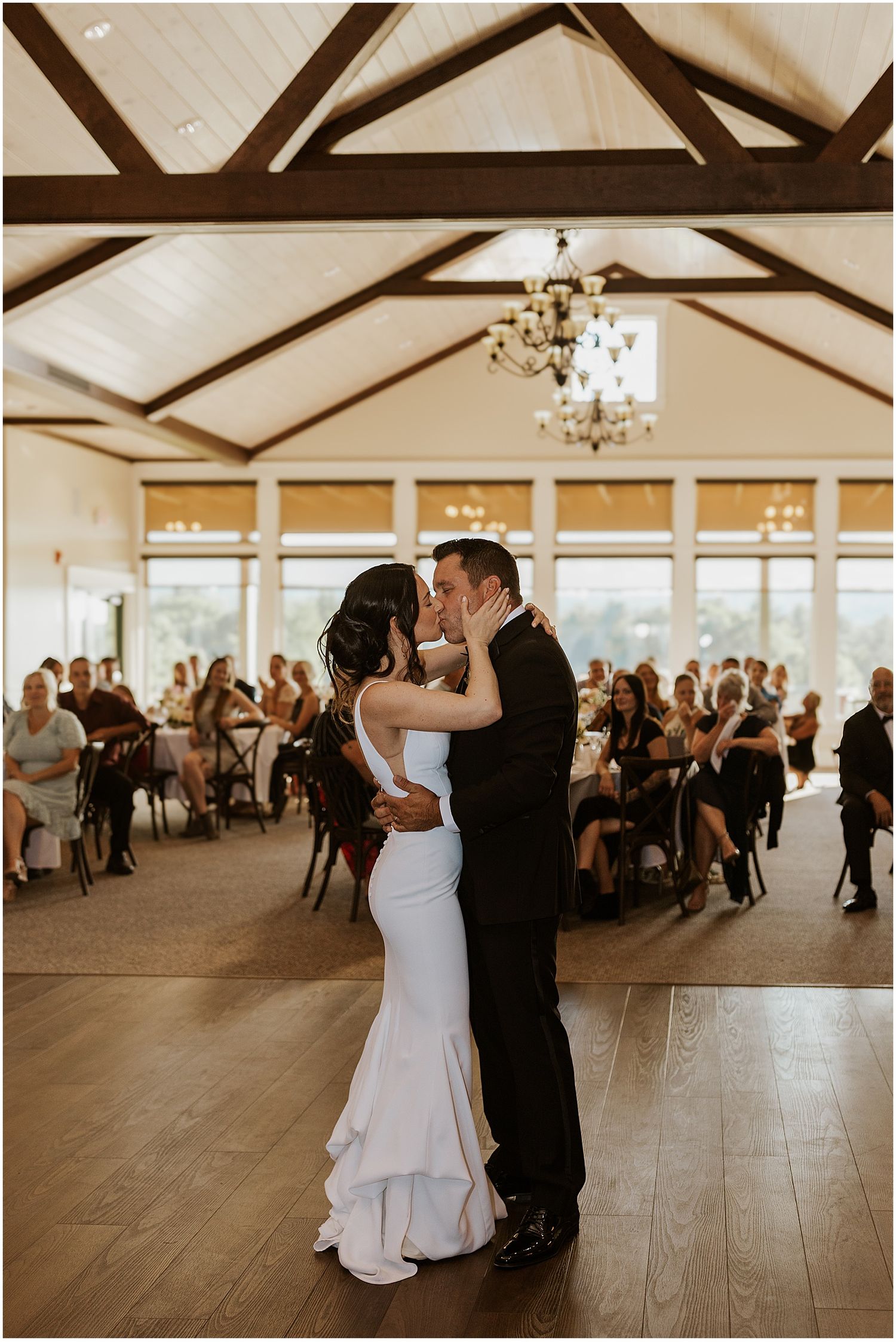 Wedding reception dance floor with couples dancing and guests watching in an elegant venue.