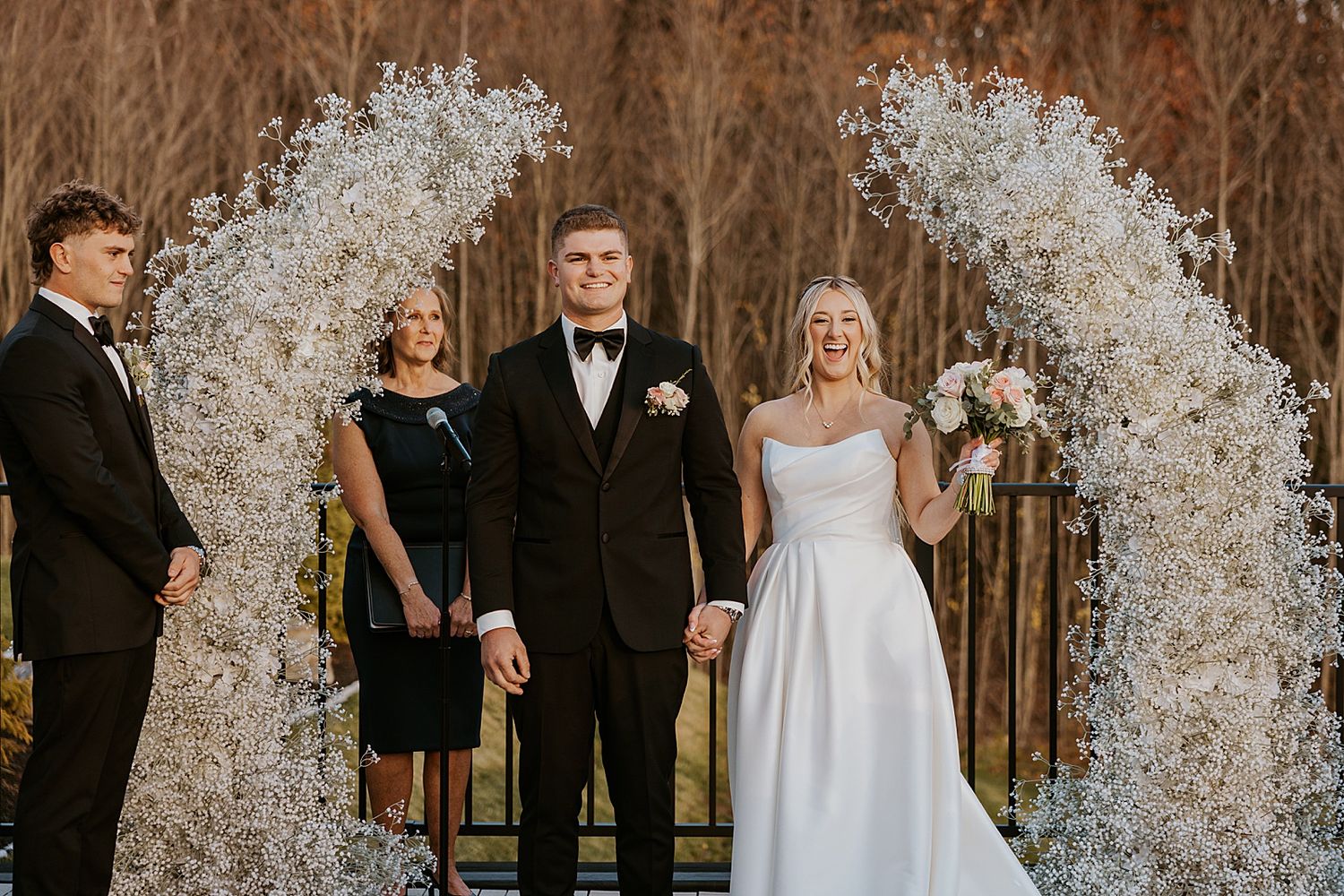 Bride and groom under a floral arch after their wedding ceremony at Hyla Brook Estate in NH