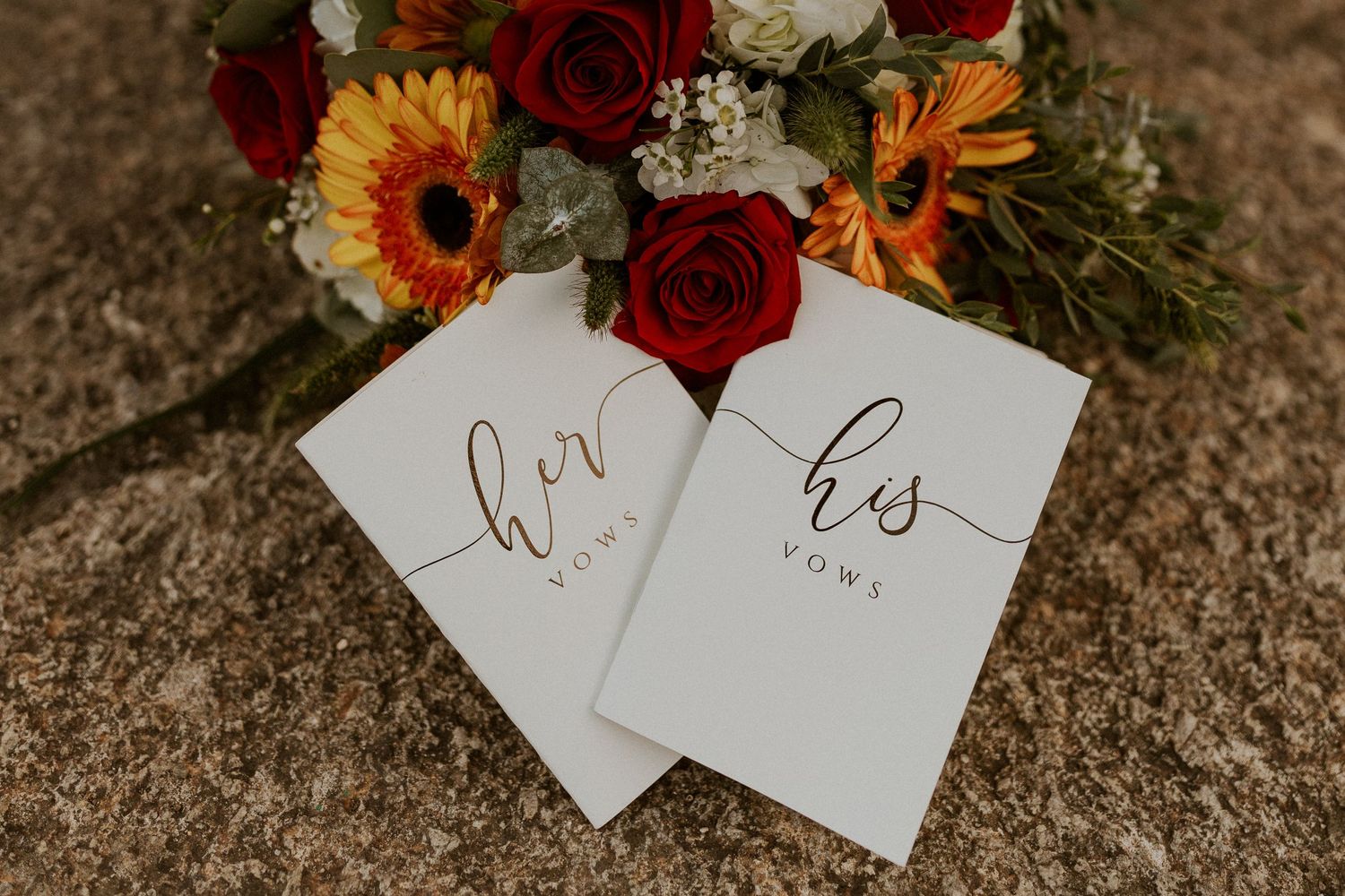 The vow books and fall colored bouquet of flowers.