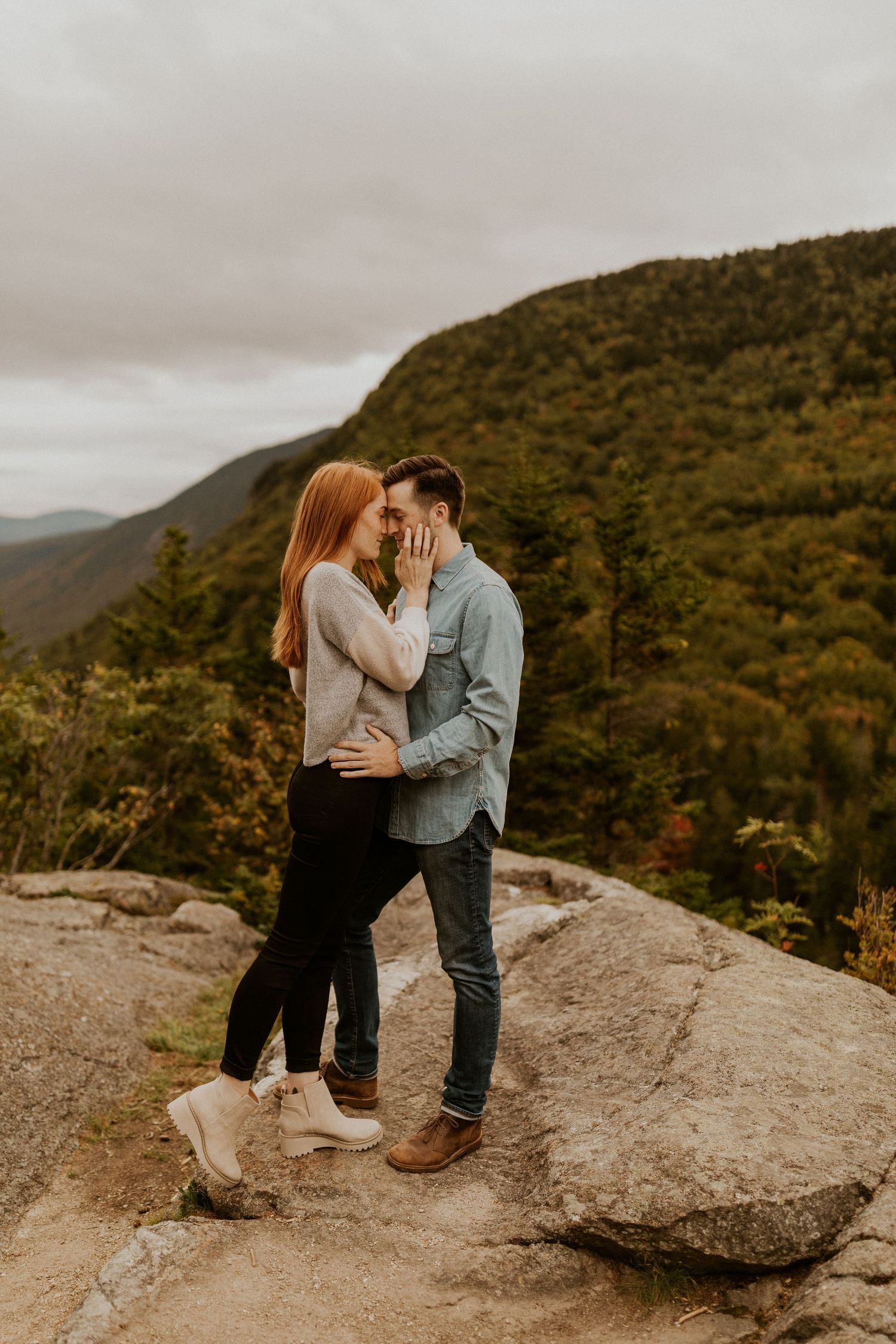 Sam and Colin embracing each other on a mountaintop in New Hampshire during their adventure engagement session