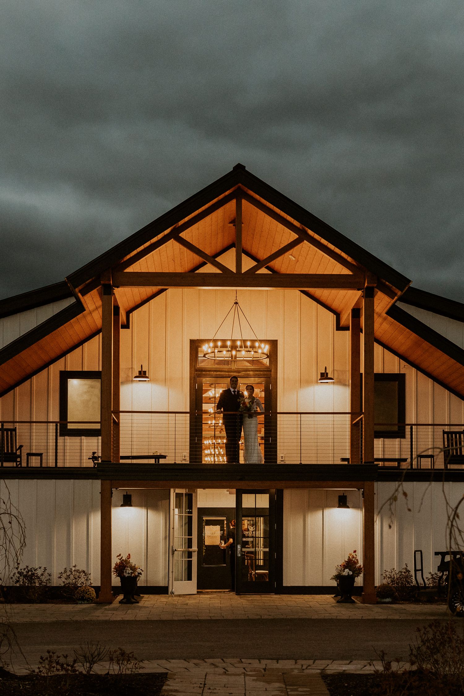 A photo of bride and groom on the balcony of the Lake House at Owl's Nest Resort at night time when it was dark outside.