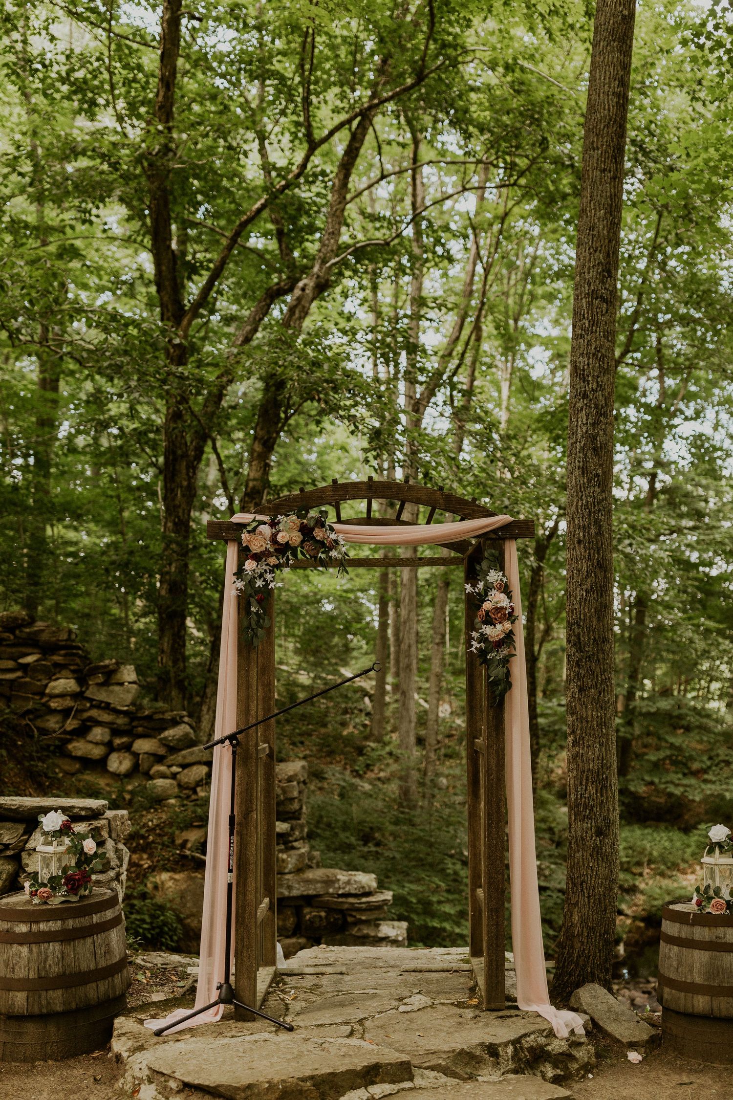 The ceremony arbor surrounded by green trees and a waterfall in the background.