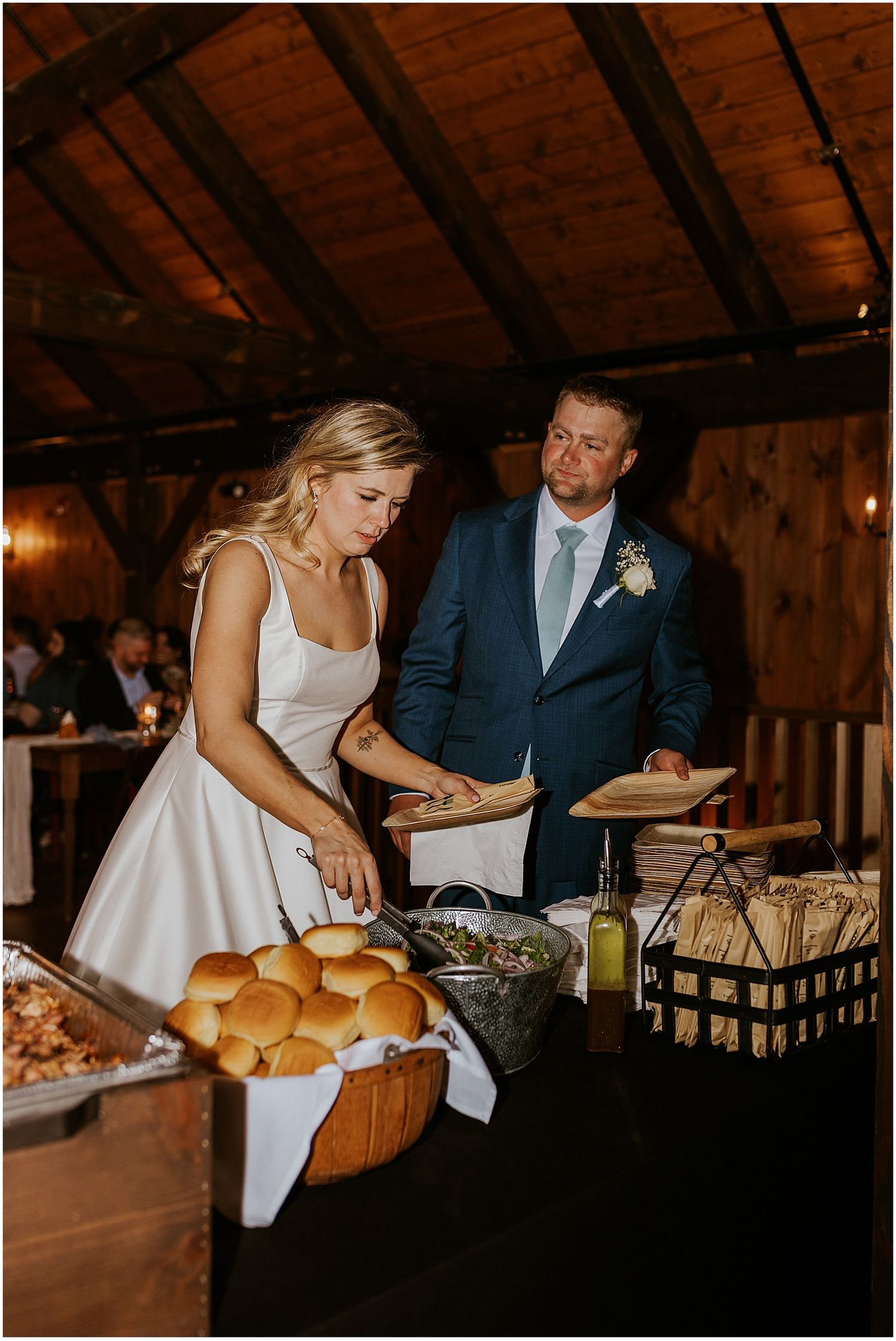 Wedding buffet setup with bread rolls and serving stations in a rustic barn setting.