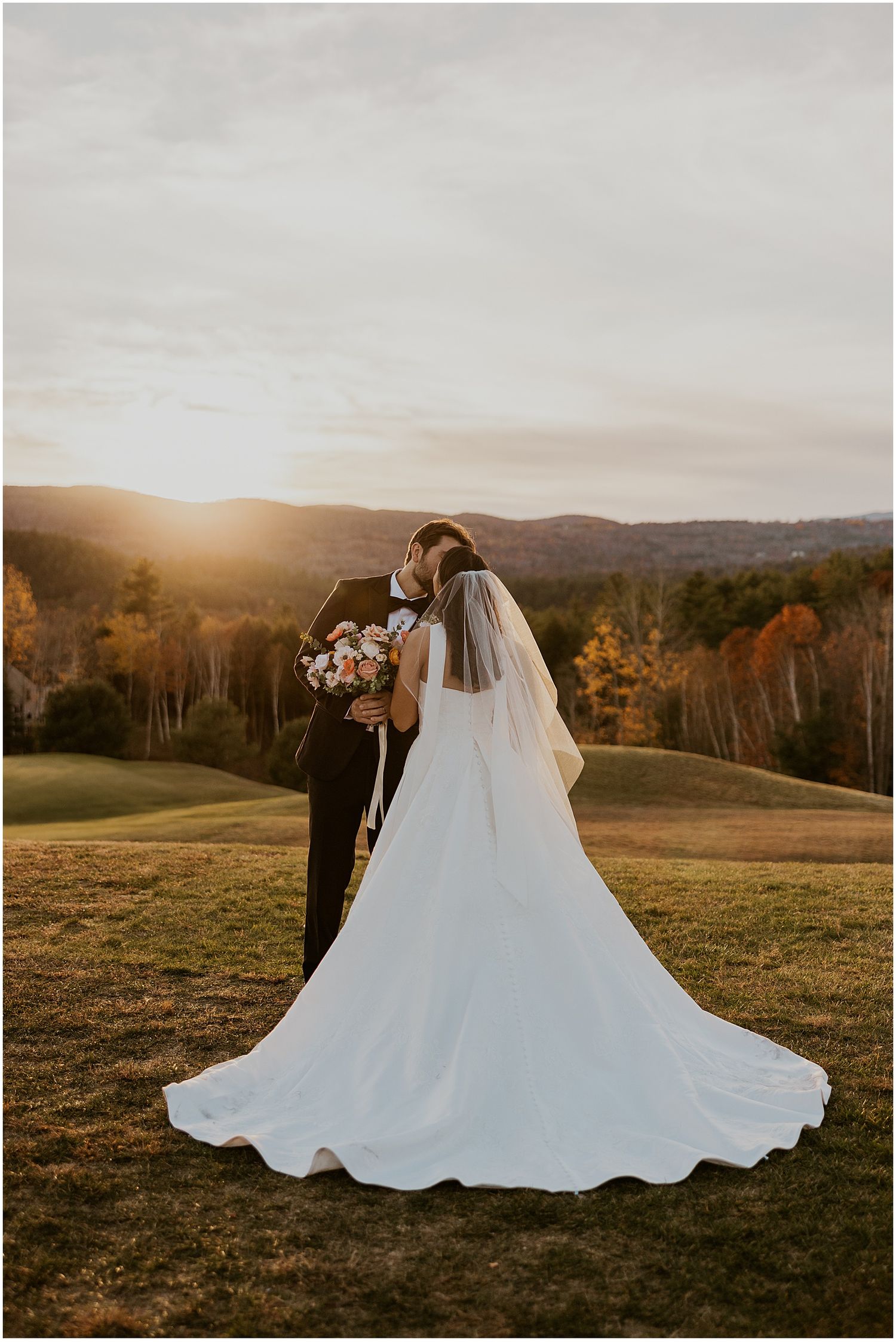 Elegant wedding dress flowing in the wind against mountain landscape at sunset.