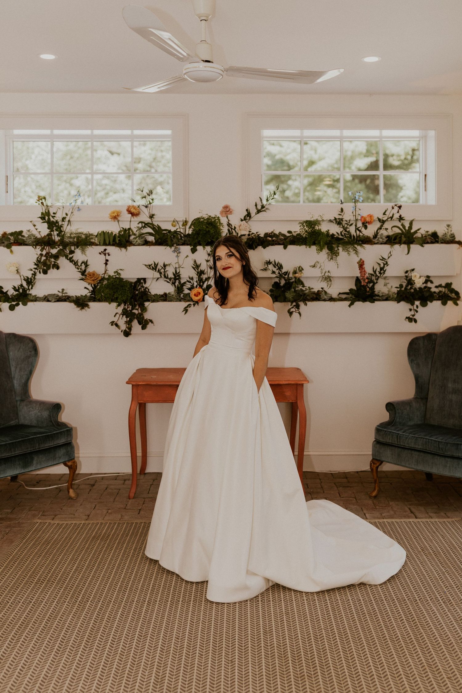 Elegant wedding venue featuring vintage furniture and hanging floral garlands in a bright white room.