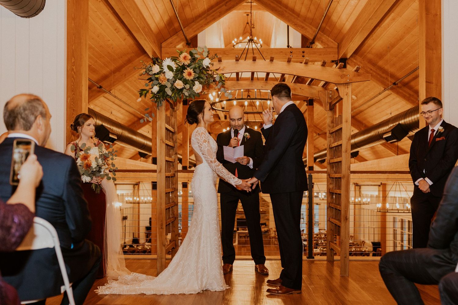 Bride and groom holding hands while exchanging vows in the new Lake House at Owl's Nest Resort in Thornton NH