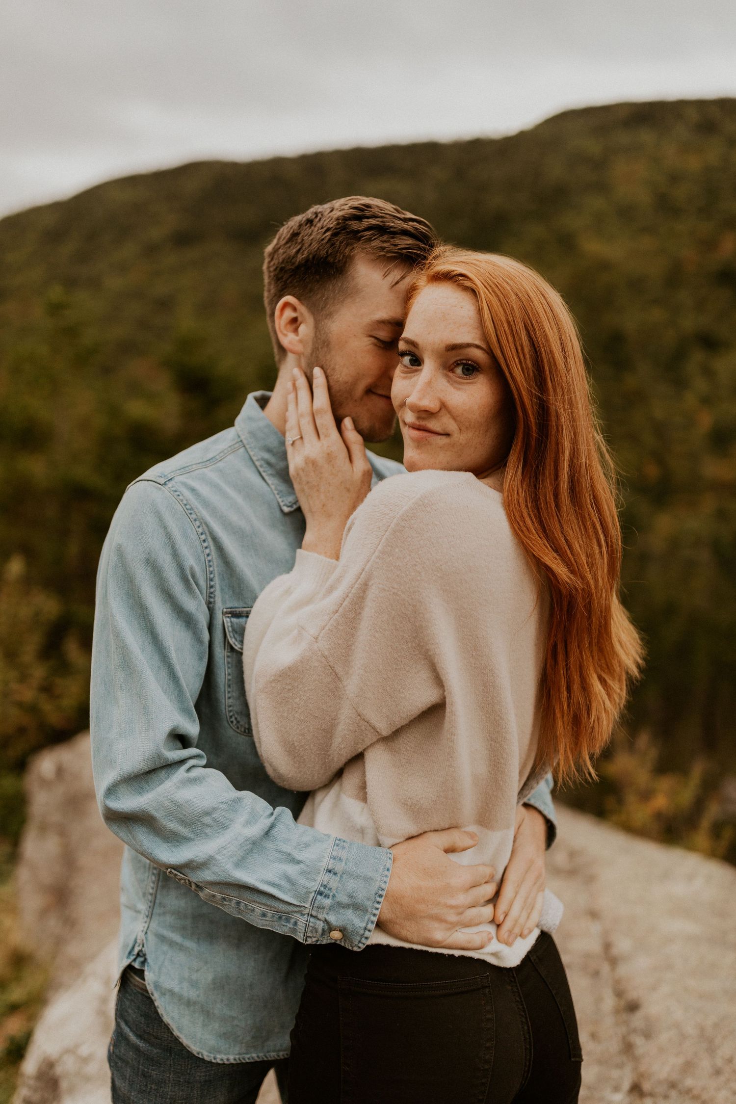Sam and Colin embracing each other on a mountaintop in New Hampshire during their adventure engagement session