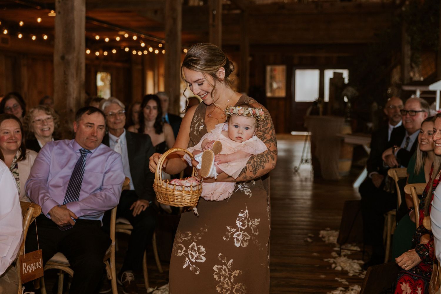 Rustic barn wedding ceremony with string lights and wooden beams.