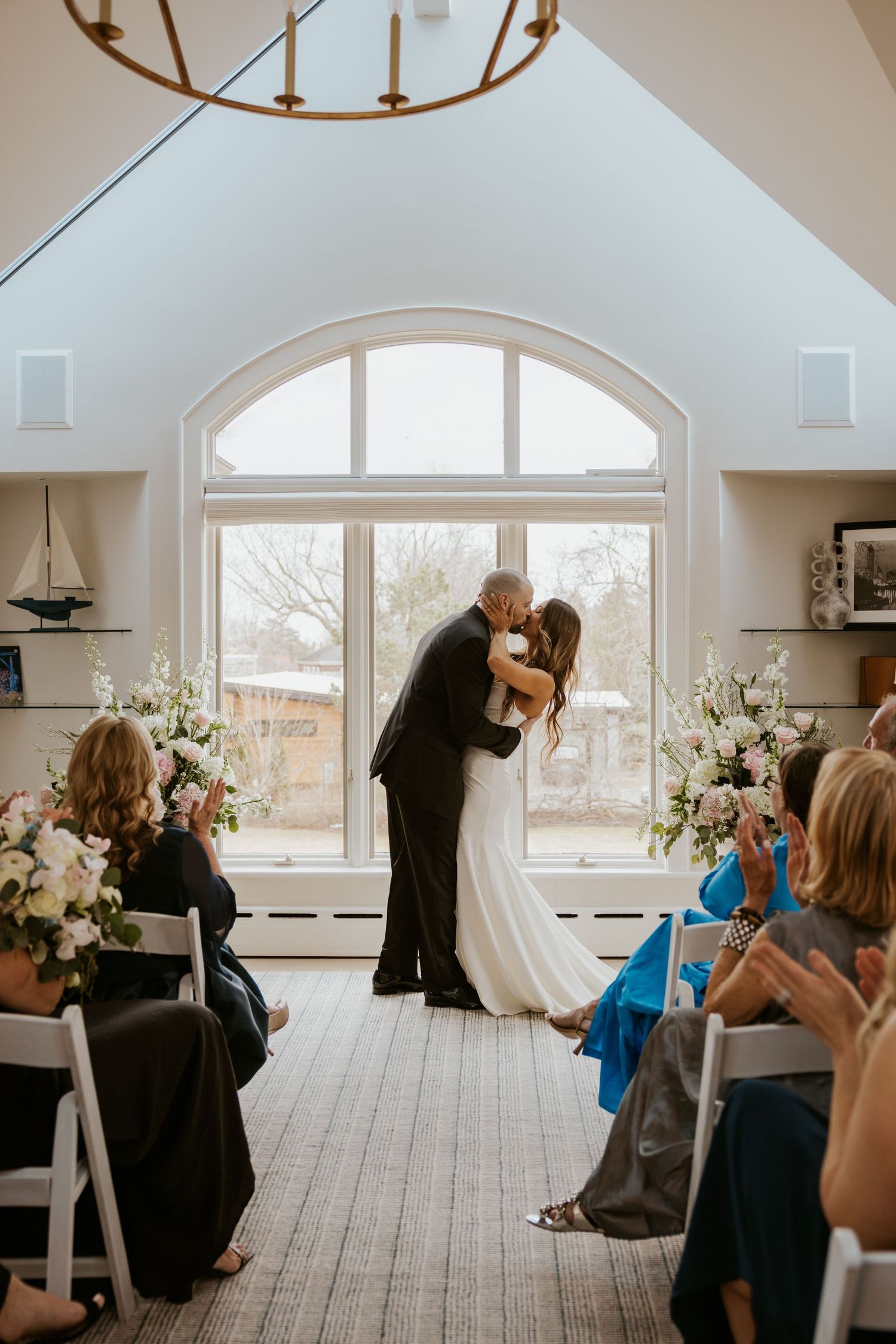 A sequence of candid moments during a wedding ceremony in a bright, airy room with arched windows.