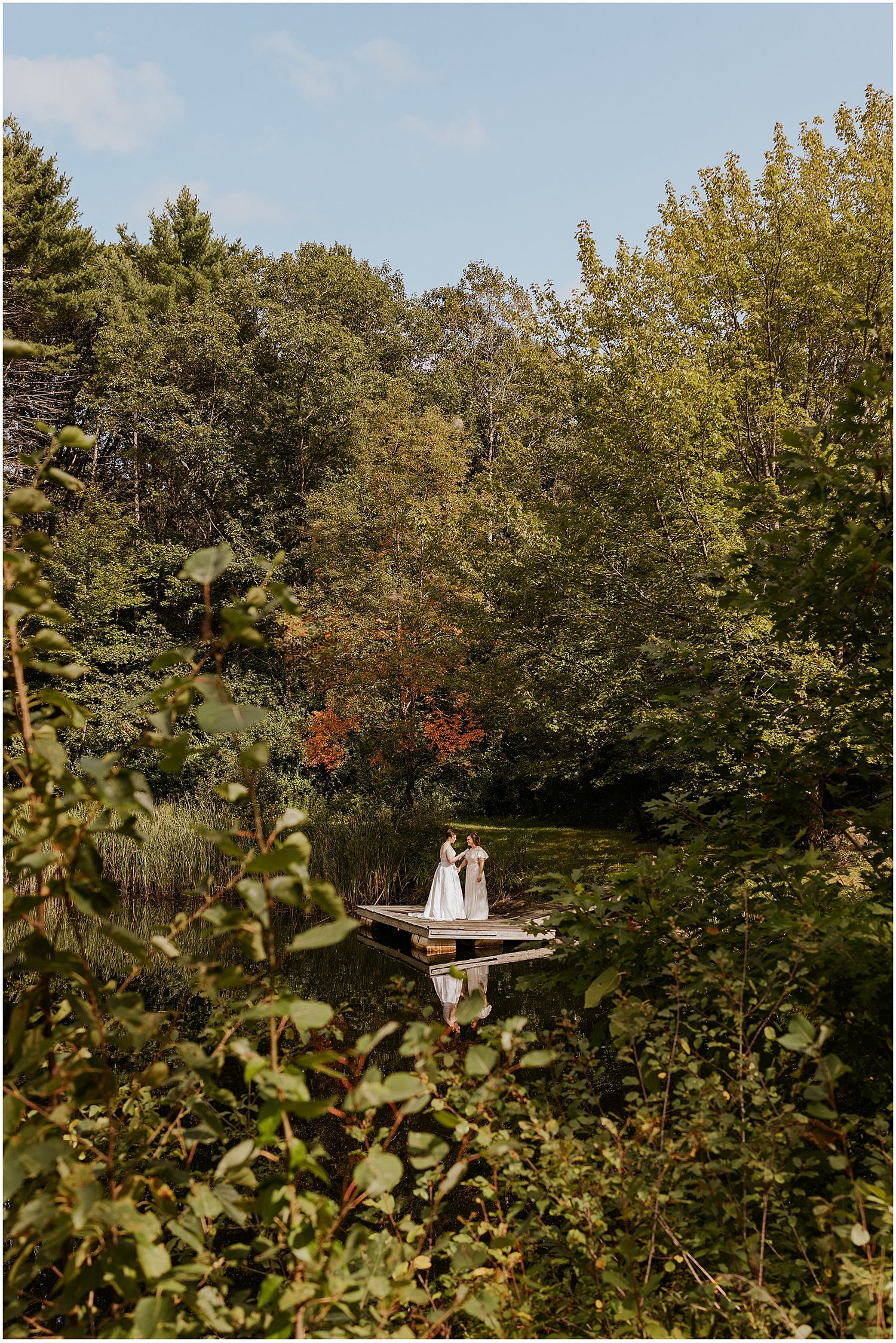 Brides reading their private vows on a wooden dock on a lake at their NH wedding at Longlook Farm
