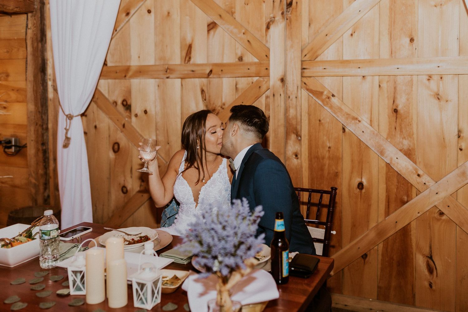 Wedding celebration in a timber-framed barn with elegant table settings and romantic lighting.