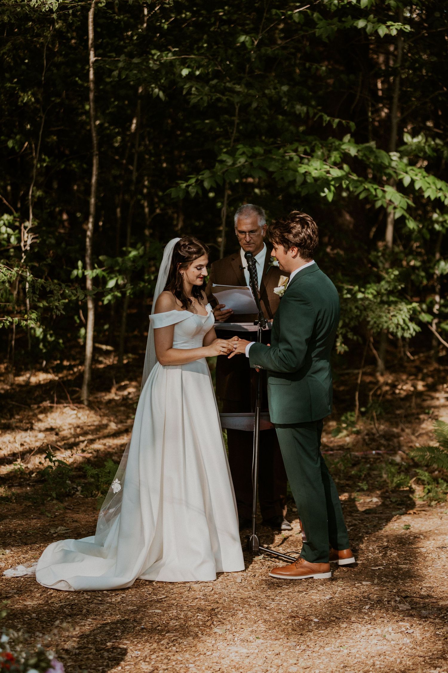 Intimate wedding ceremony exchange in a peaceful forest setting.