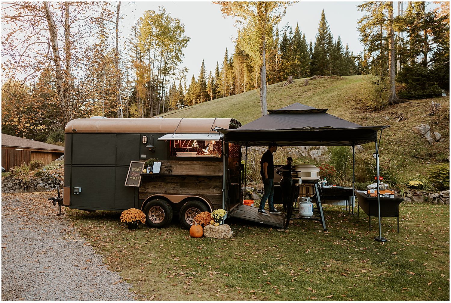 Row of food trucks and vendors set up outdoors at an autumn event.