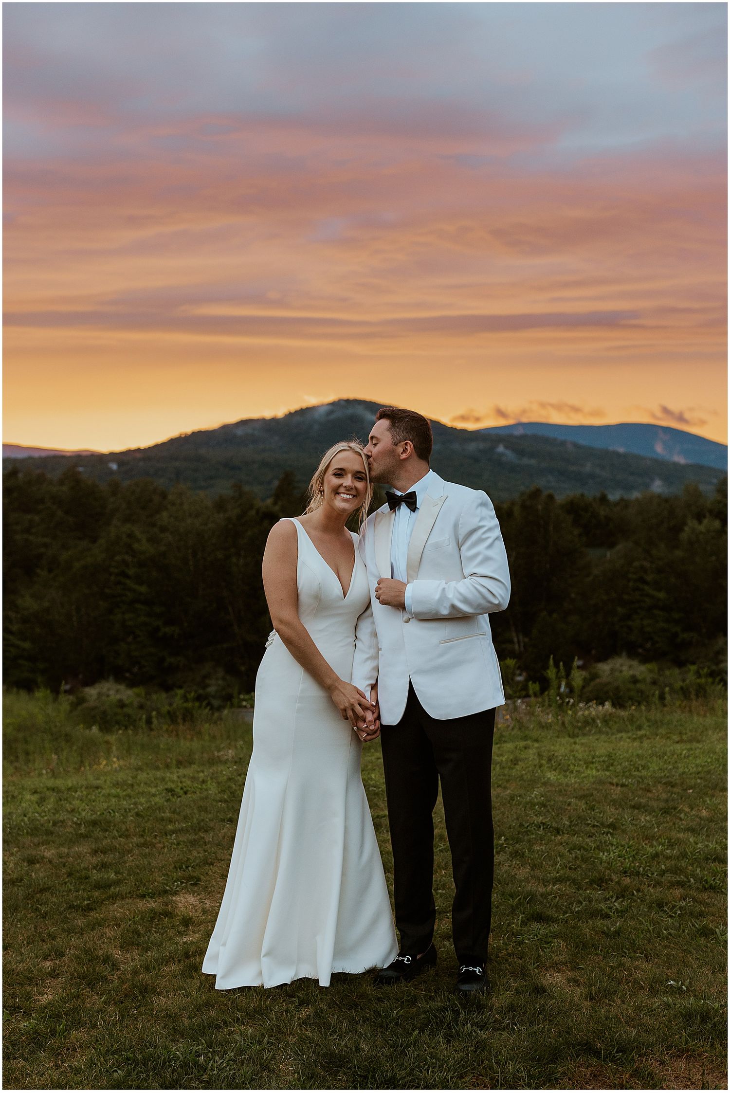 A couple shares an intimate wedding moment at sunset in front of a mountain landscape at Owls Nest Resort NH