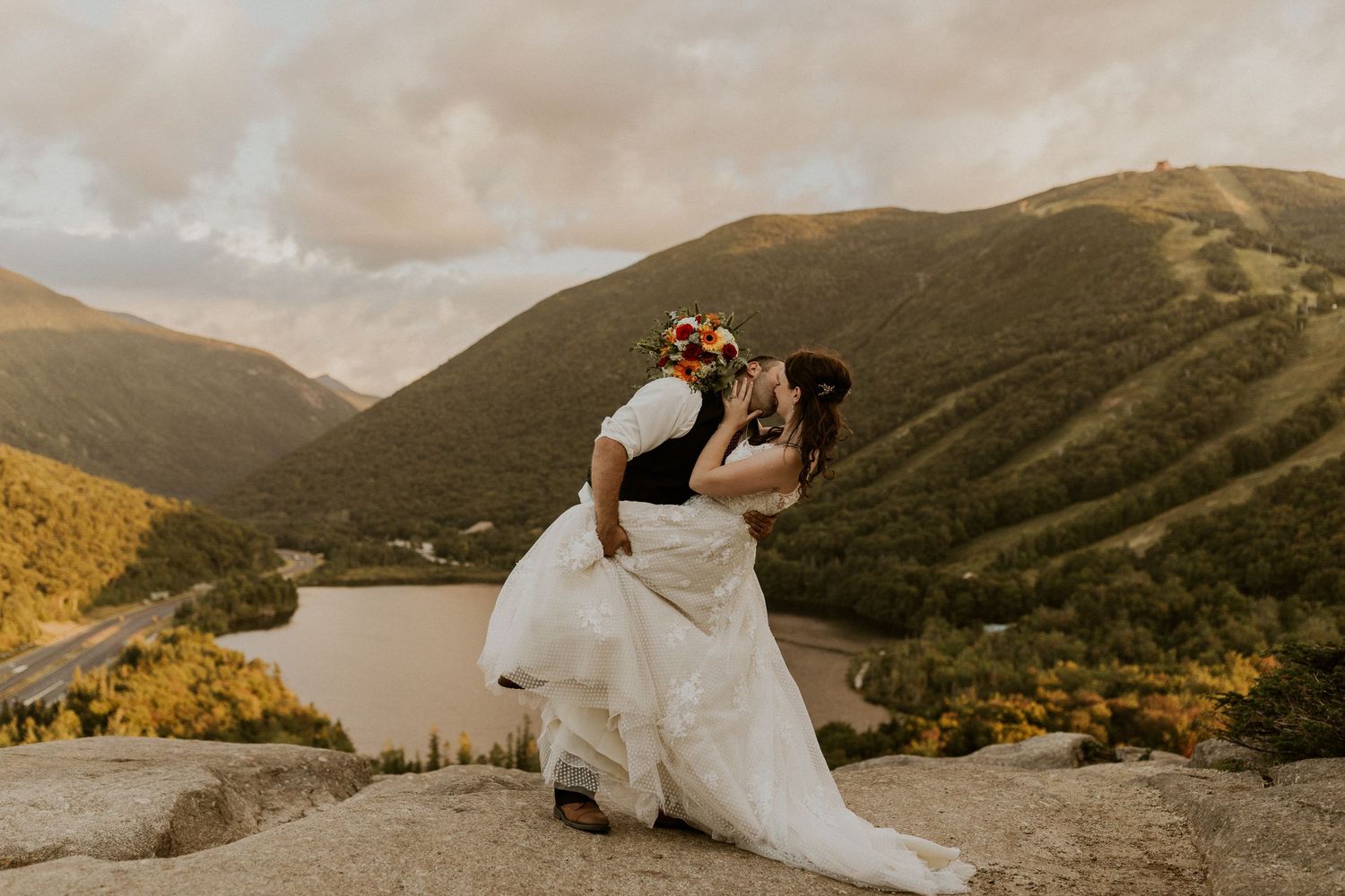 Newlyweds dipping and kissing on a New Hampshire Mountain top.