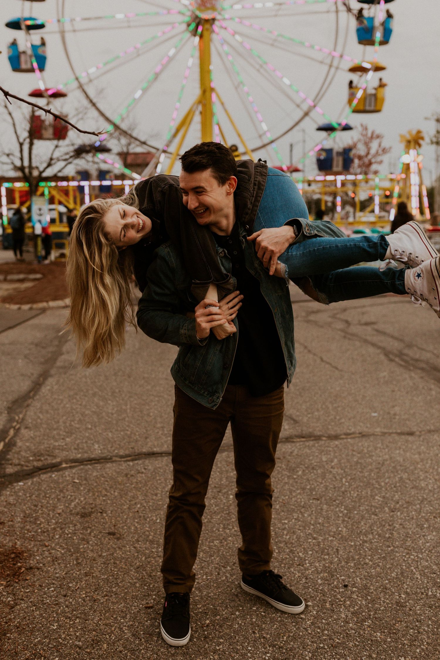Couple performing a romantic dip dance move with a ferris wheel in the background.