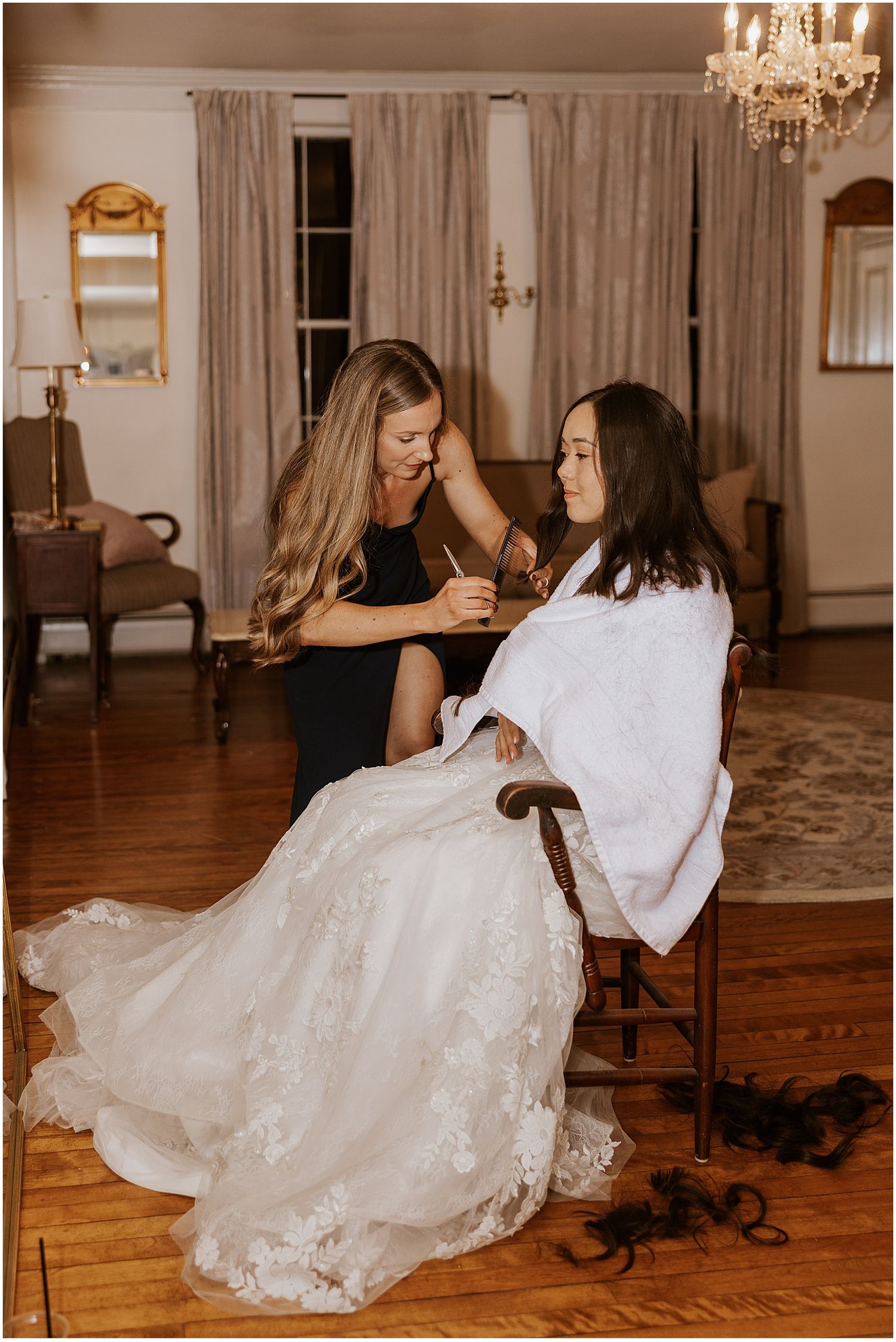 Wedding dress flowing across hardwood floor in elegant room with chandelier.