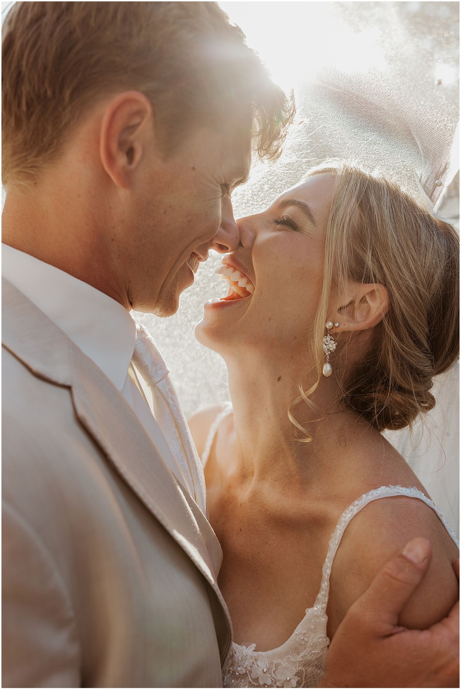 Sunlit close-up wedding portrait capturing an intimate moment between newlyweds.