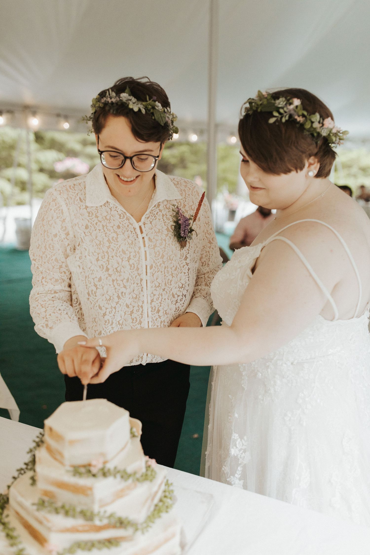 A couple cuts their elegant white wedding cake together during their reception celebration.